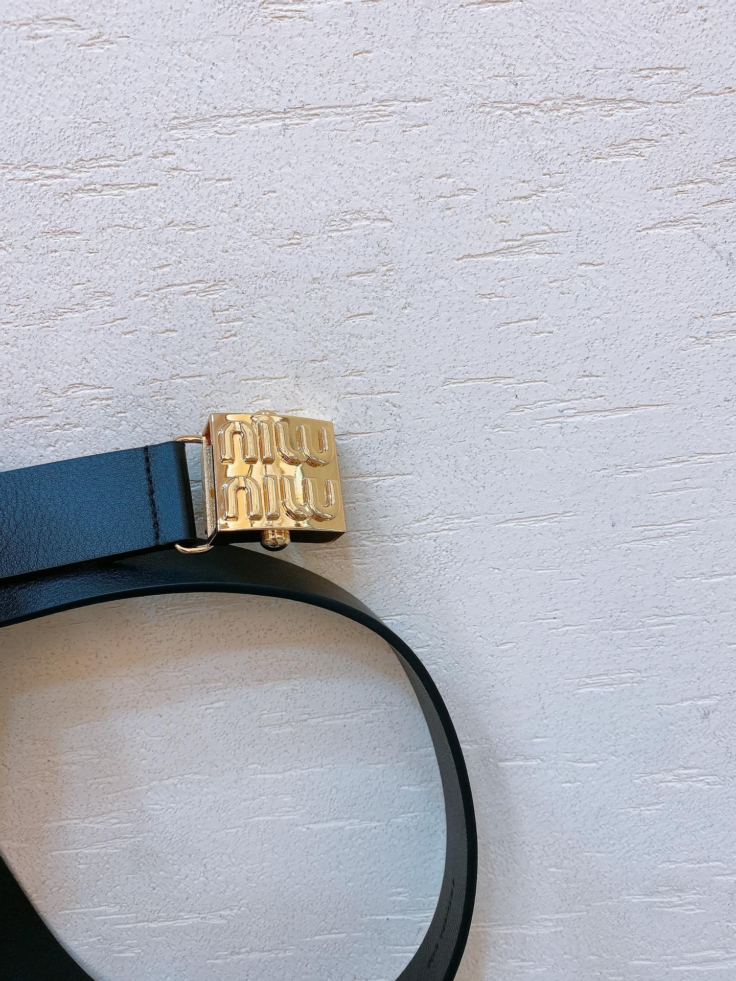 Black leather belt with gold metal buckle engraved with Miu Miu