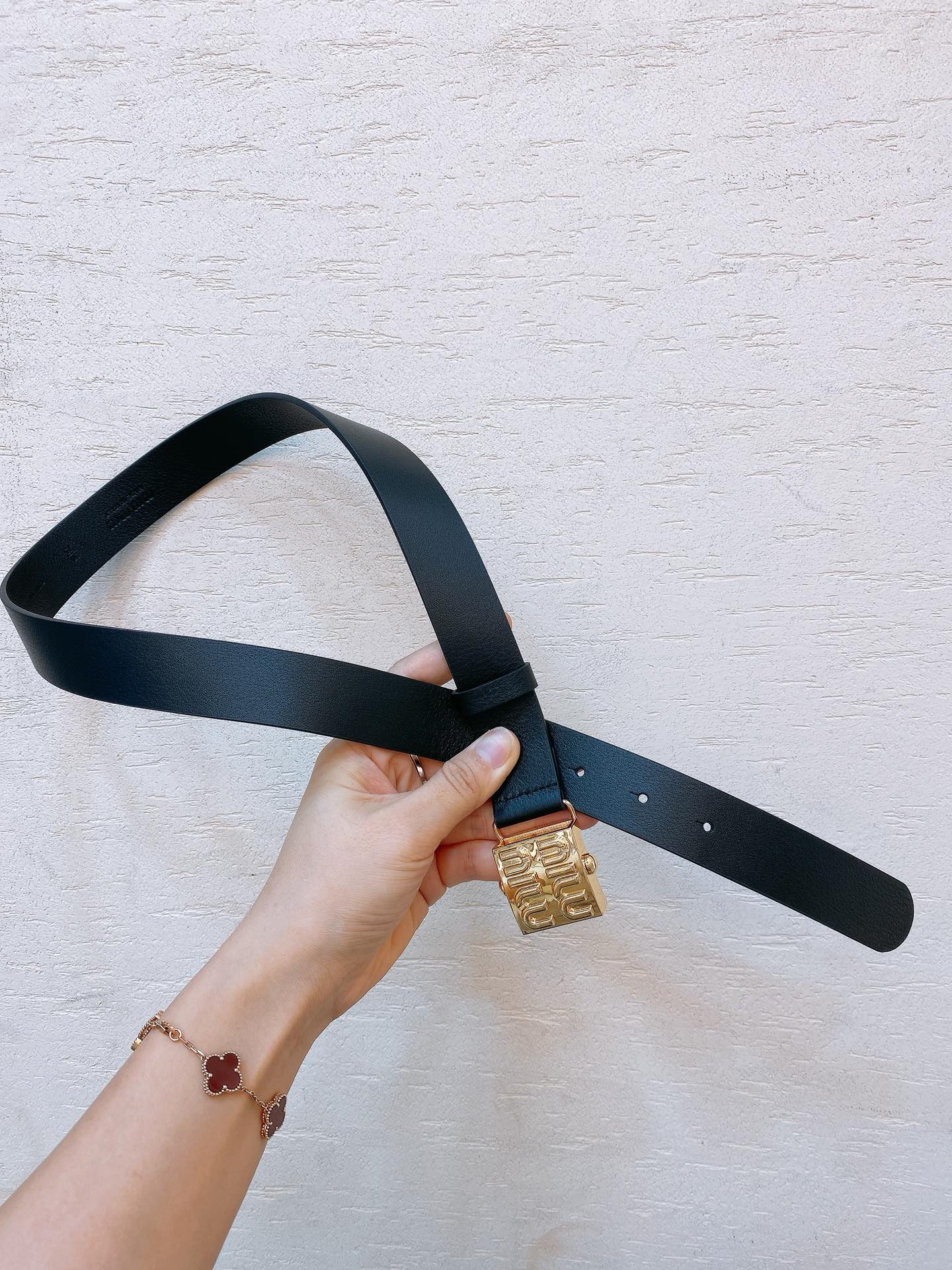 Black leather belt with gold metal buckle engraved with Miu Miu