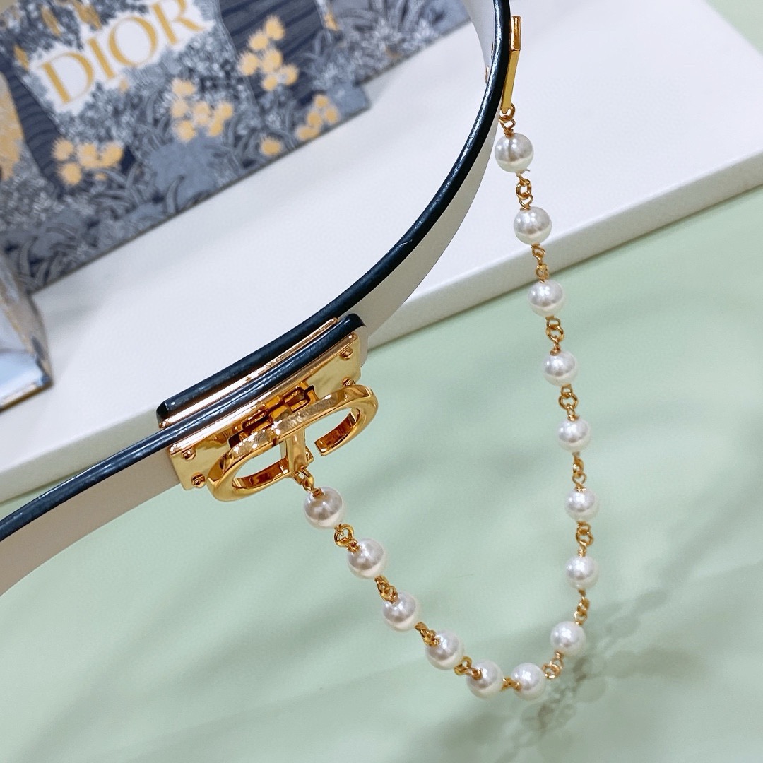 Dior belt with a "CD" buckle, accompanied by a string of pearls.