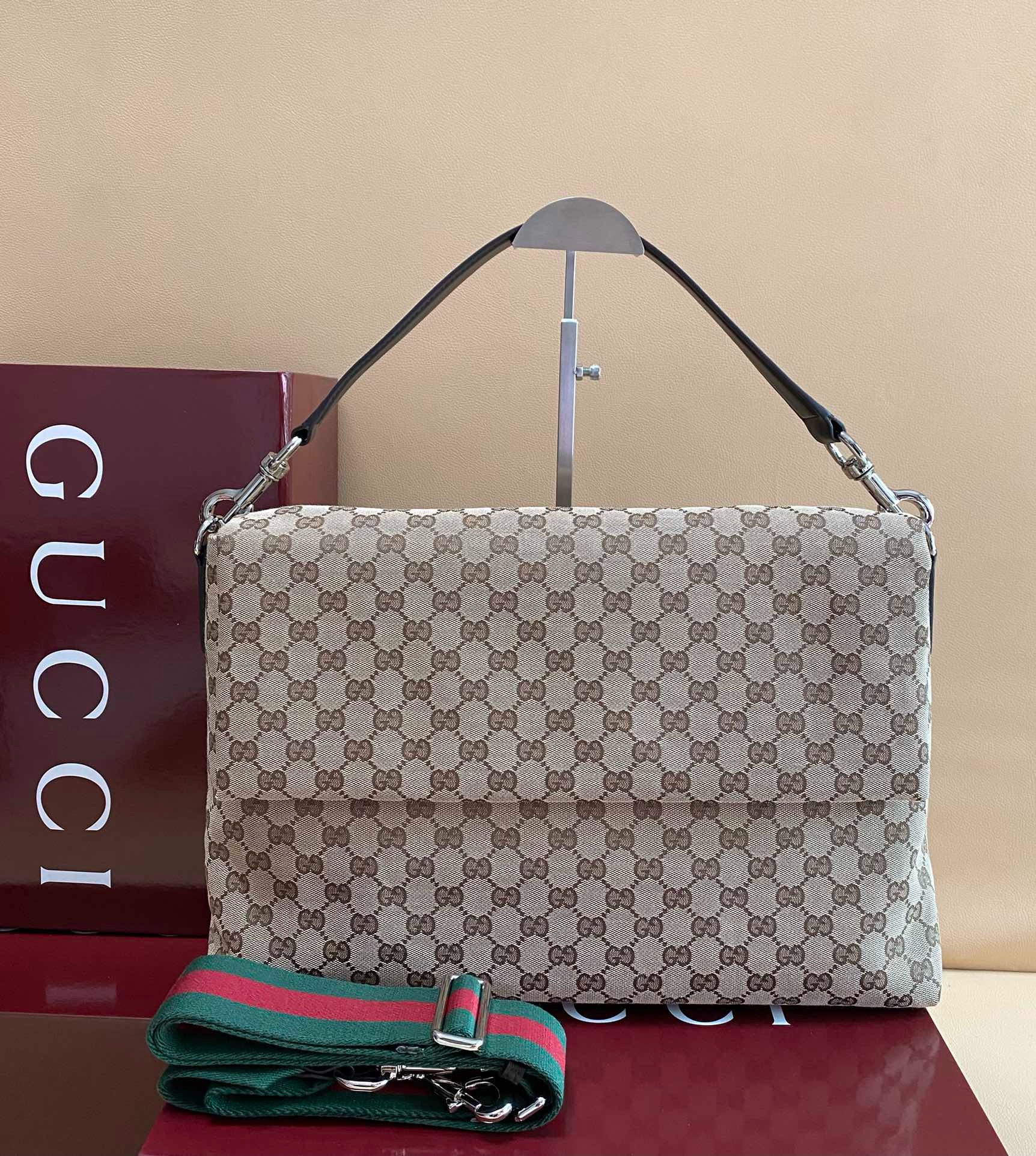 Gucci GG Canvas Crossbody bag with green and red web strap, displayed next to a Gucci box.