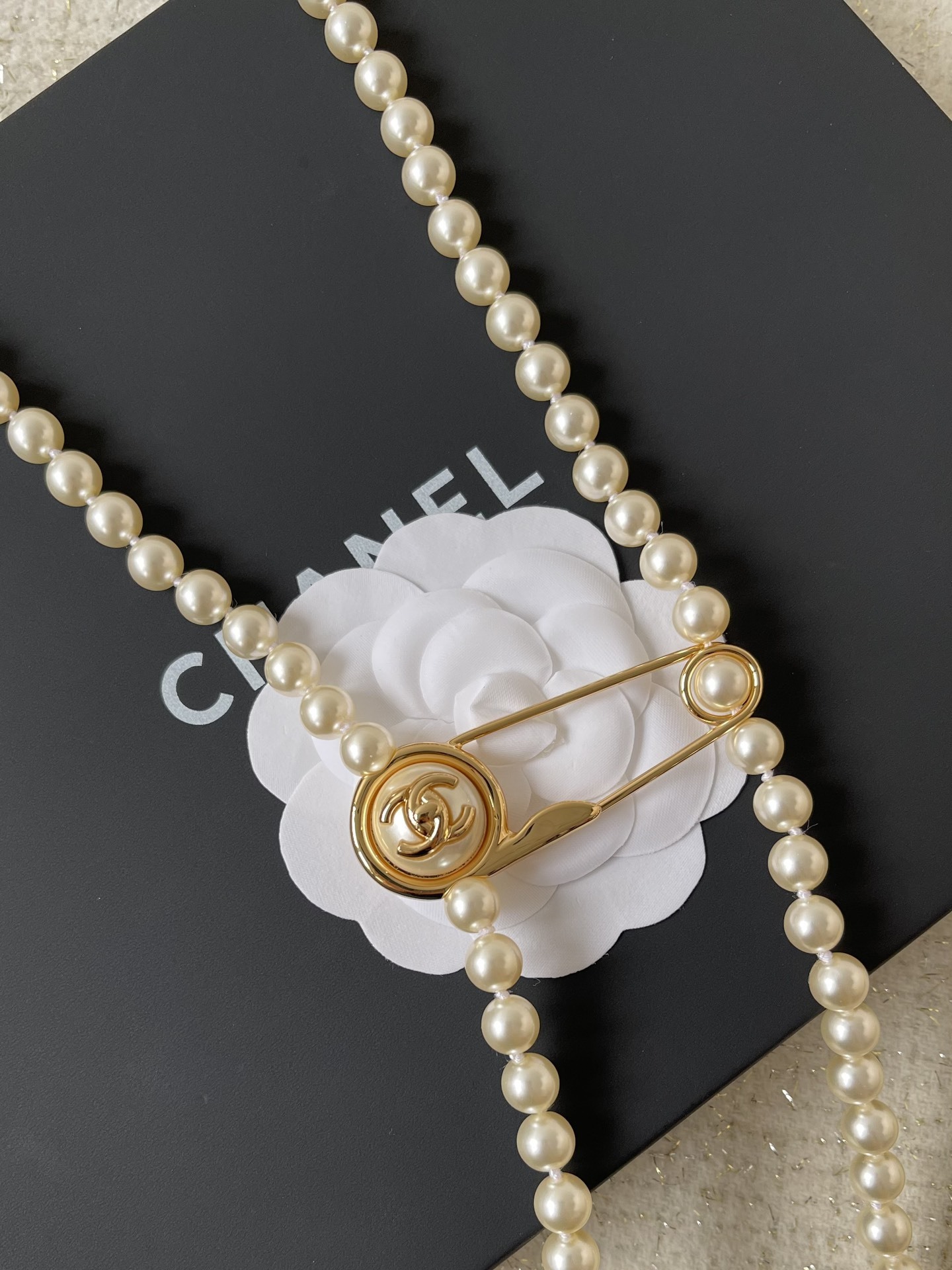 Elegant Long Pearl Necklace with Gold Safety Pin Logo Pendant