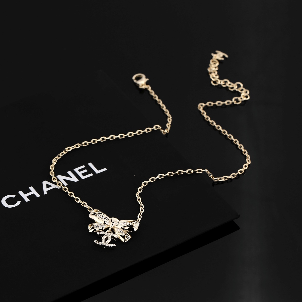 Elegant Gold Ribbon Bow Necklace with Sparkling CC Pendant