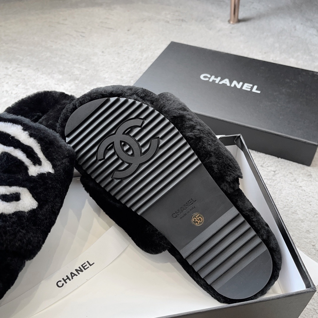A pair of black Chanel plush fur slides featuring a large white CC logo, presented on a black Chanel shoebox with white ribbon. - Hình 9