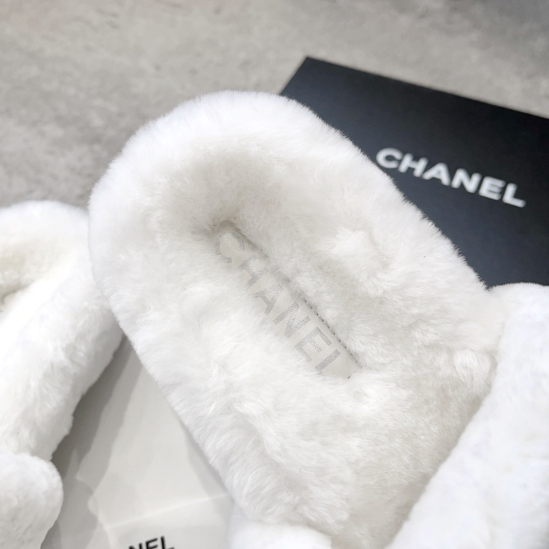 A pair of white plush faux fur slippers with a black interlocking CC logo resting on a luxury black gift box - Hình 8