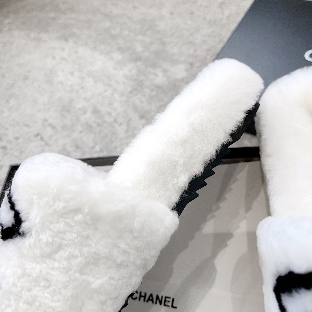 A pair of white plush faux fur slippers with a black interlocking CC logo resting on a luxury black gift box - Hình 7