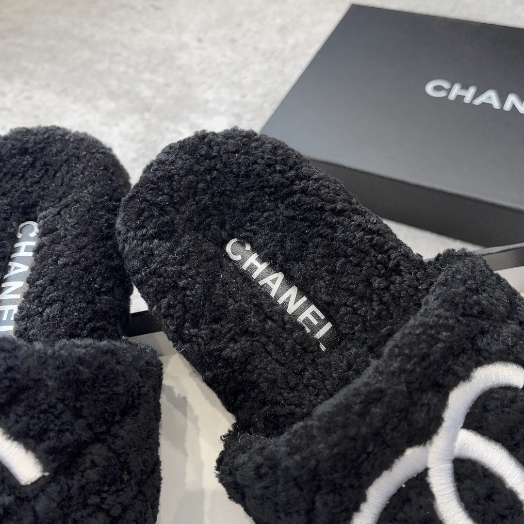 A pair of black fluffy shearling-style slippers with a white interlocking CC logo sitting on a black designer box - Hình 8