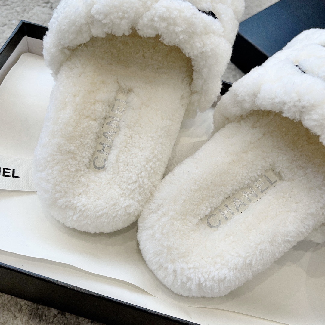 A pair of premium white fuzzy shearling slides with a black interlaced logo displayed on a designer shoebox. - Hình 9