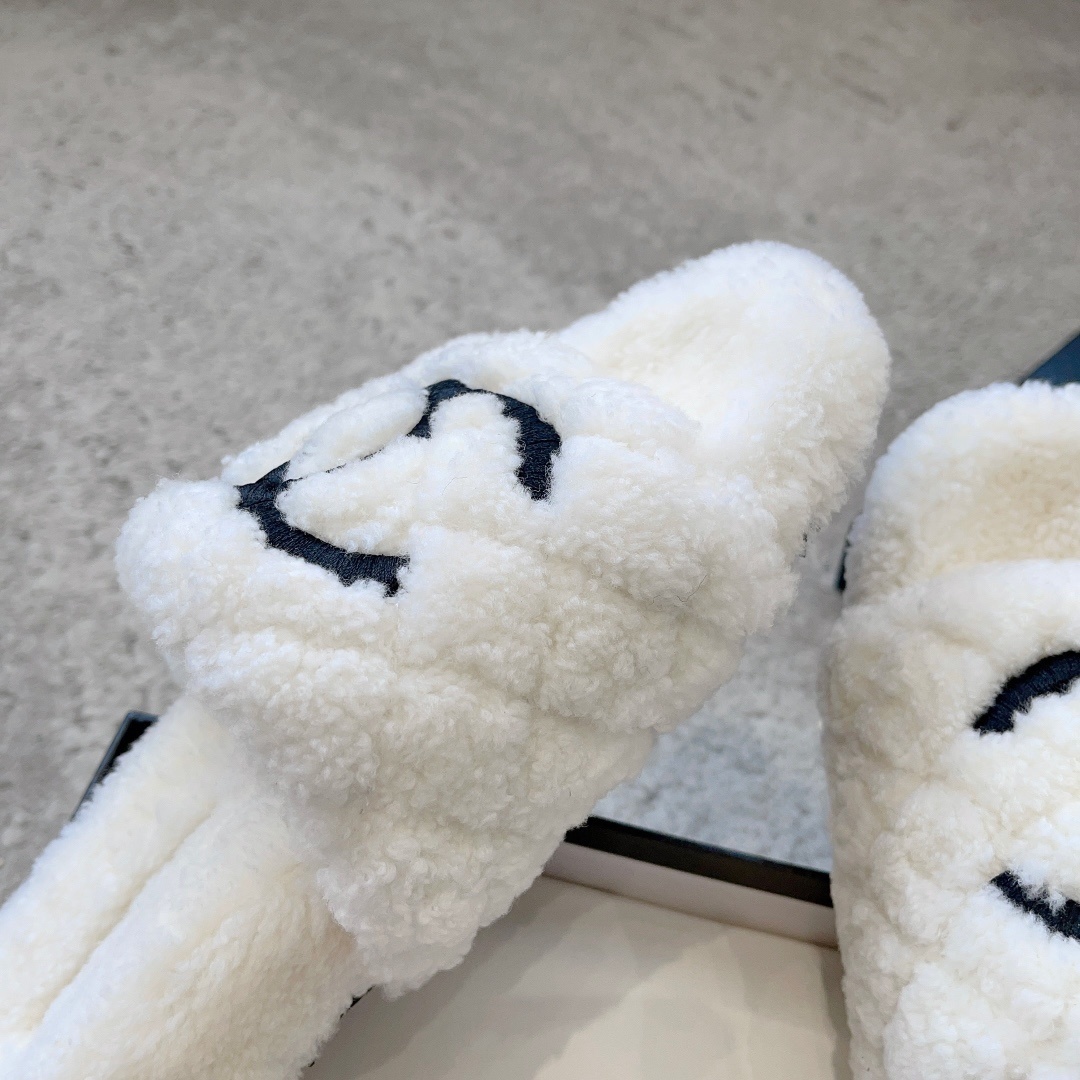A pair of premium white fuzzy shearling slides with a black interlaced logo displayed on a designer shoebox. - Hình 7