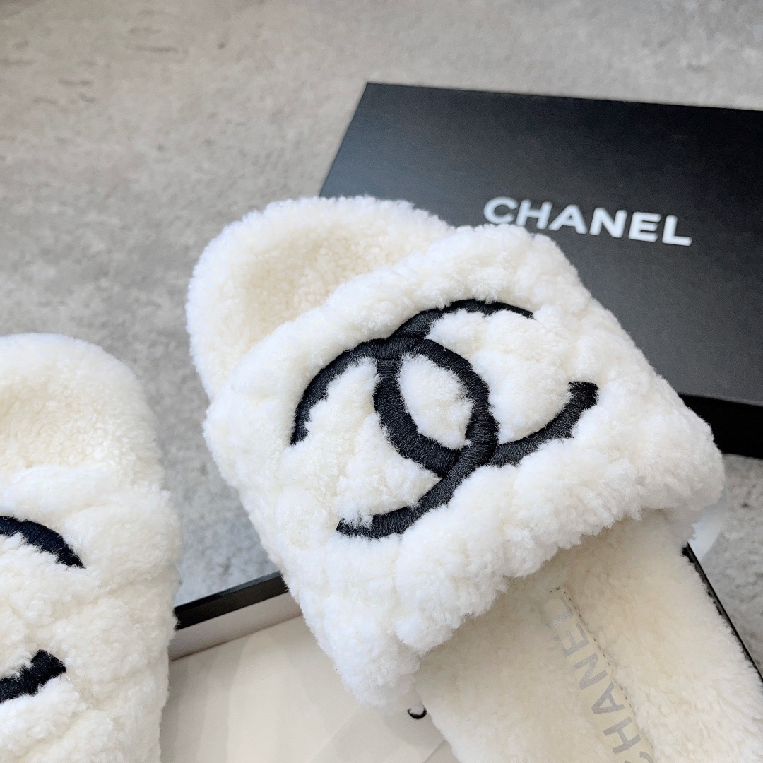 A pair of premium white fuzzy shearling slides with a black interlaced logo displayed on a designer shoebox. - Hình 6