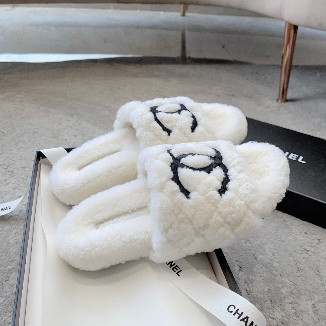 A pair of premium white fuzzy shearling slides with a black interlaced logo displayed on a designer shoebox. - Hình 5