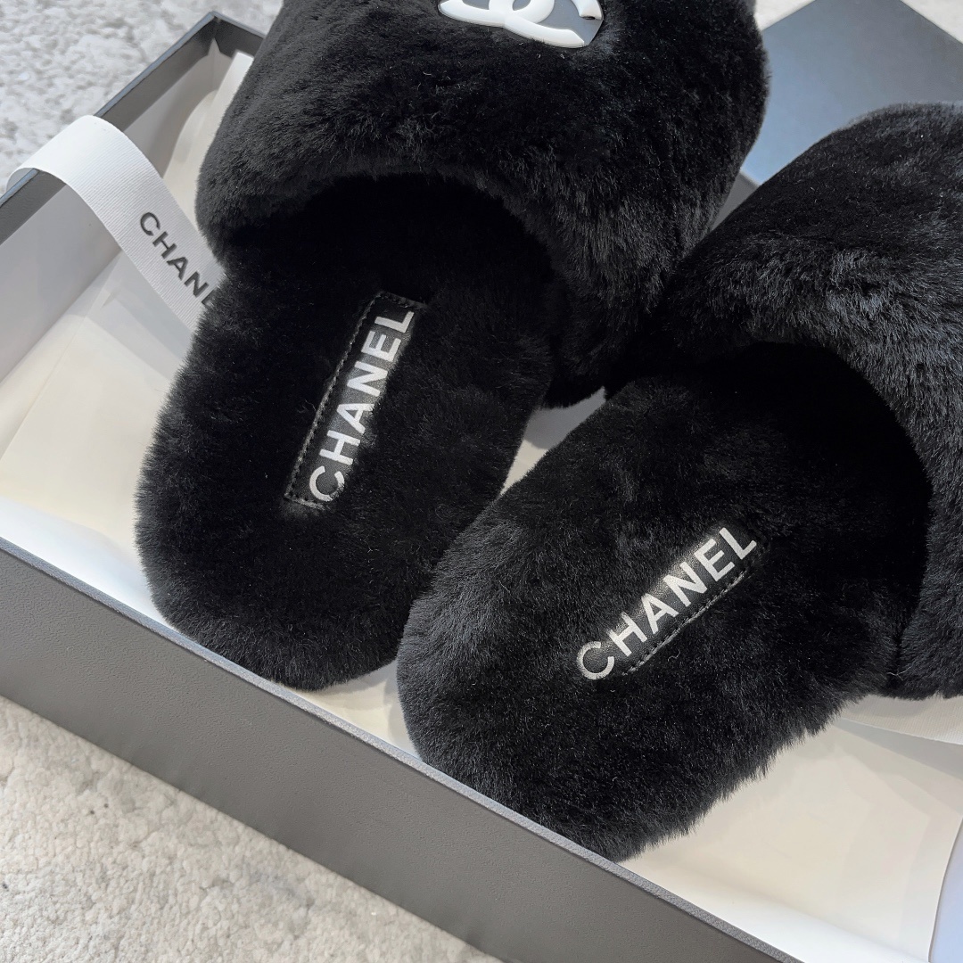 A pair of black fluffy faux fur slides with a white interlocking CC logo placed on a black designer shoe box. - Hình 8