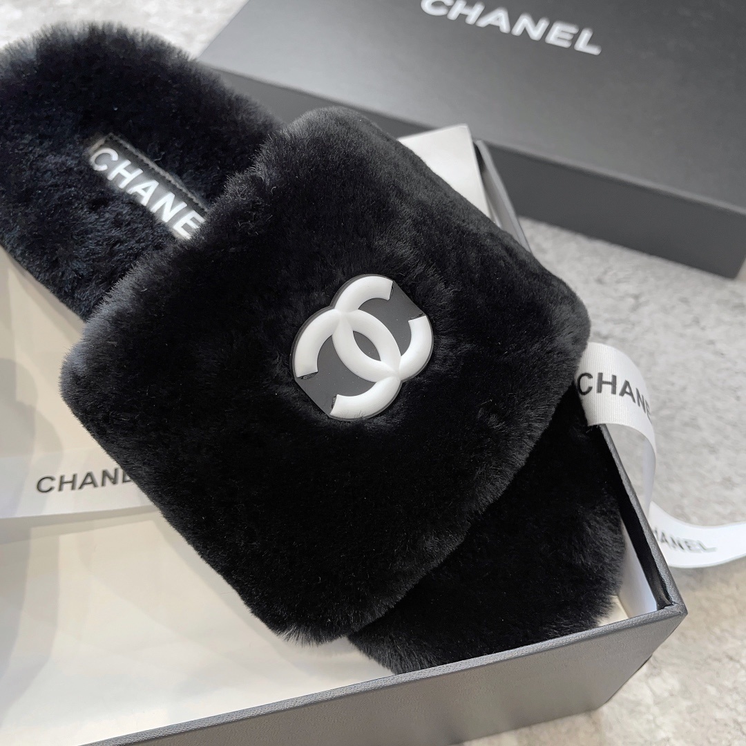 A pair of black fluffy faux fur slides with a white interlocking CC logo placed on a black designer shoe box. - Hình 6
