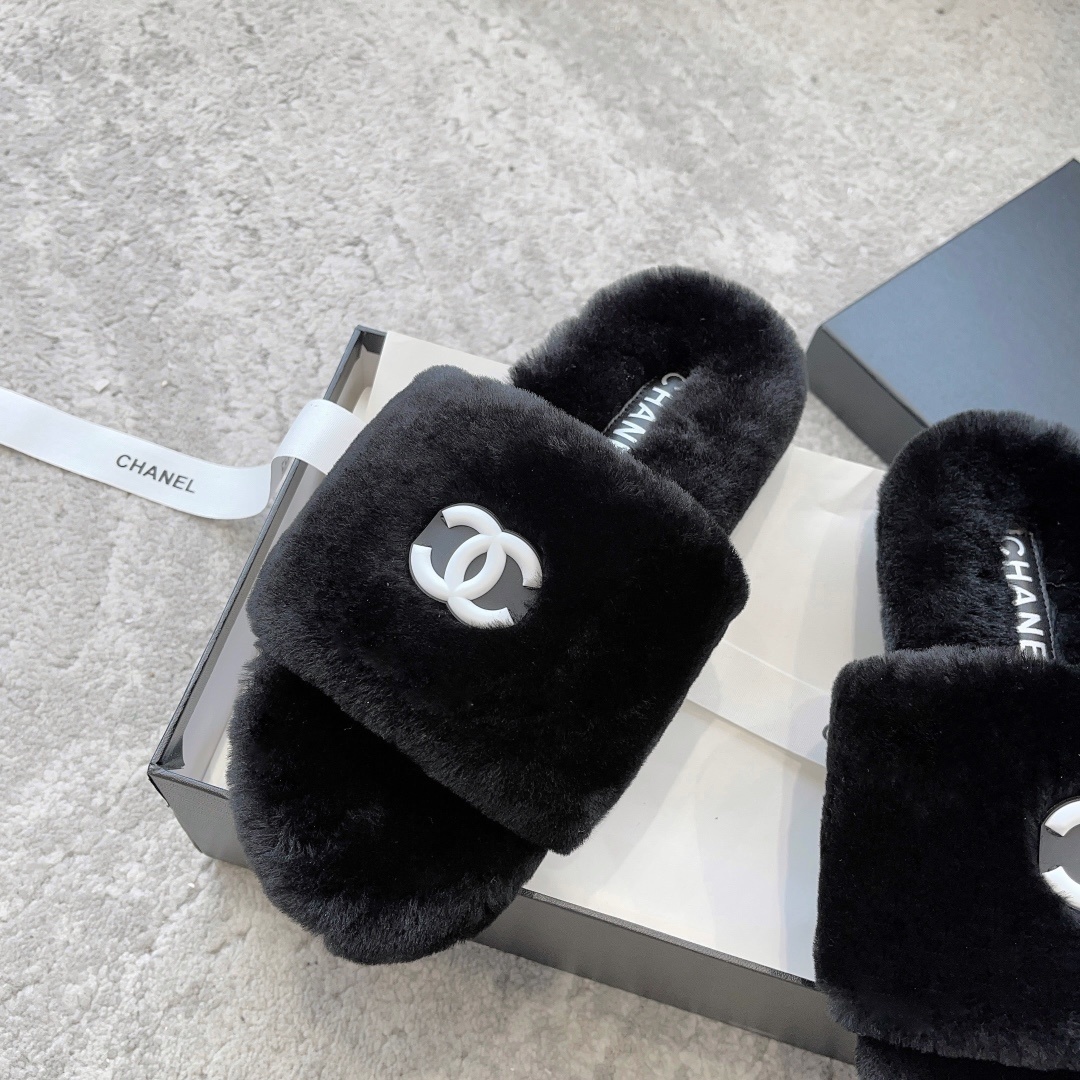 A pair of black fluffy faux fur slides with a white interlocking CC logo placed on a black designer shoe box. - Hình 5