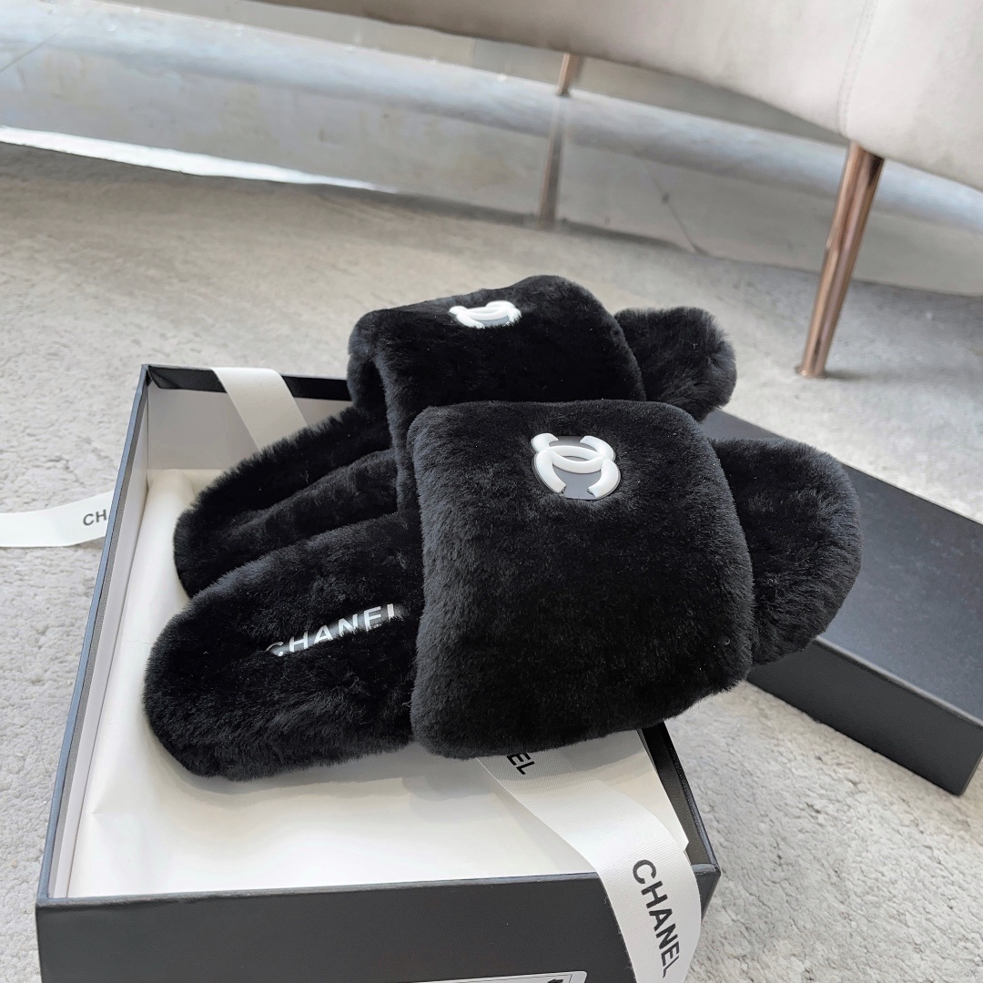 A pair of black fluffy faux fur slides with a white interlocking CC logo placed on a black designer shoe box. - Hình 4