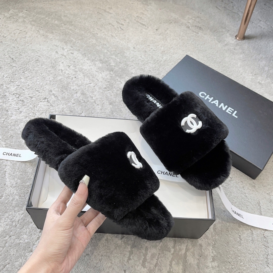 A pair of black fluffy faux fur slides with a white interlocking CC logo placed on a black designer shoe box. - Hình 3
