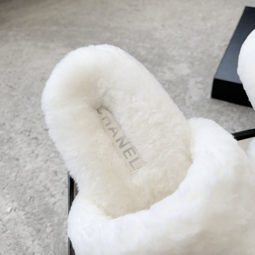 A pair of fluffy white faux fur slippers featuring a black interlaced logo, presented on a black designer box. - Hình 8
