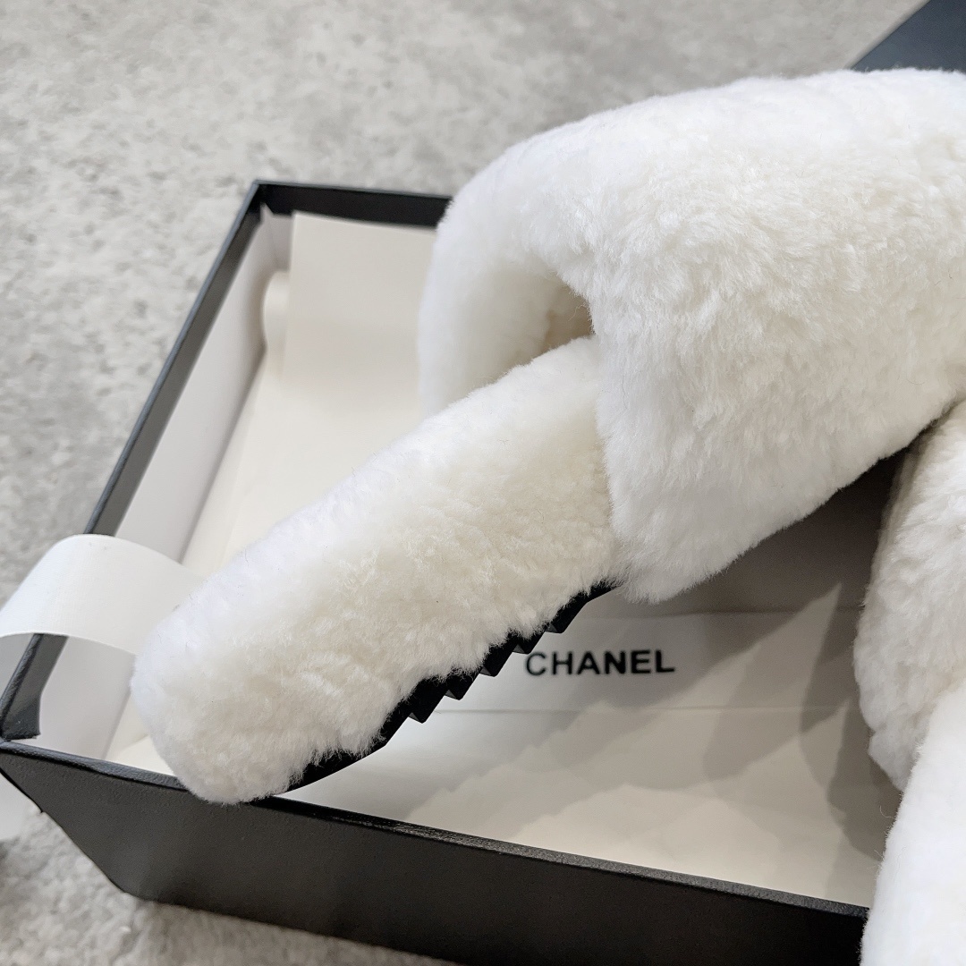 A pair of fluffy white faux fur slippers featuring a black interlaced logo, presented on a black designer box. - Hình 7