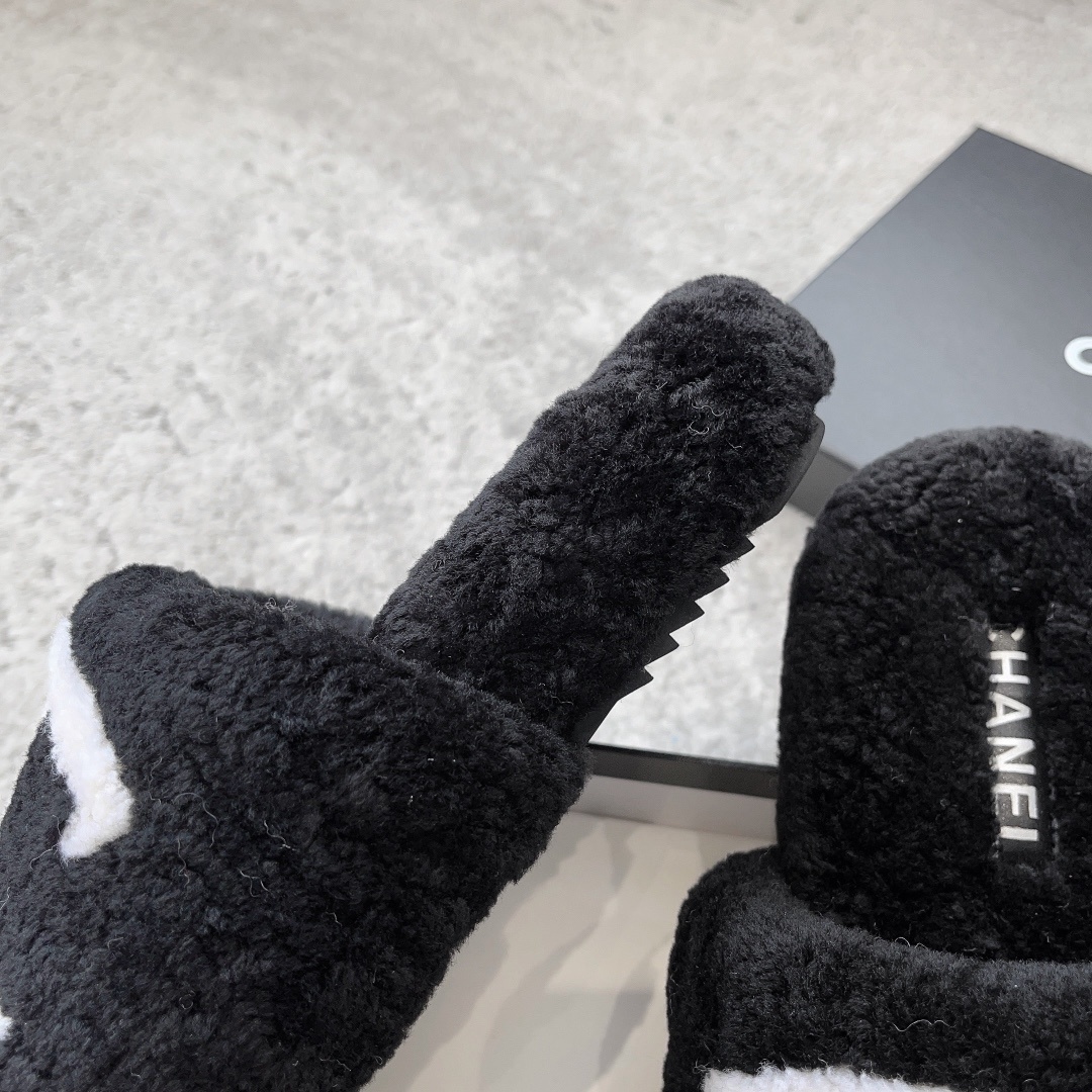 A pair of black fuzzy Chanel shearling slippers with a large white interlocking CC logo, presented in a black Chanel box with a white ribbon. - Hình 8