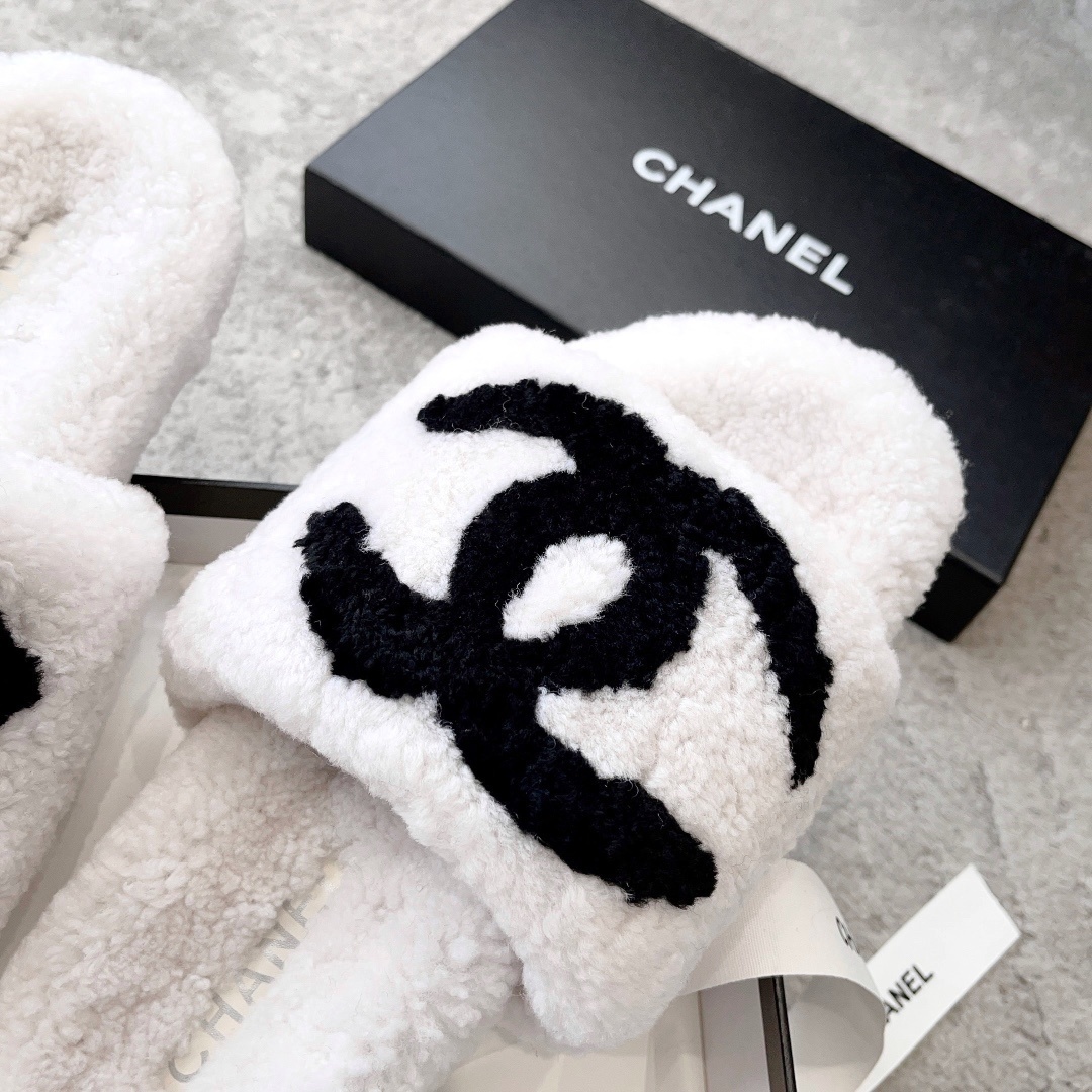 Pair of white plush shearling slides with black interlocking CC logo sitting on a designer box - Hình 6