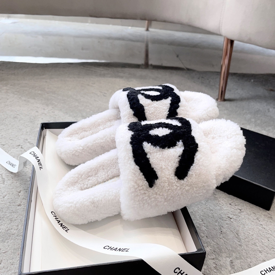 Pair of white plush shearling slides with black interlocking CC logo sitting on a designer box - Hình 5