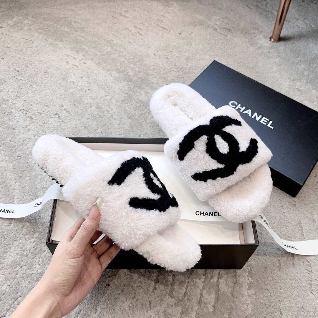 Pair of white plush shearling slides with black interlocking CC logo sitting on a designer box - Hình 3