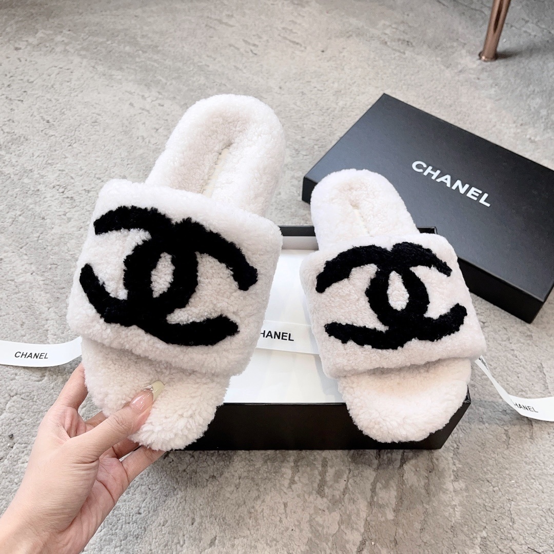 Pair of white plush shearling slides with black interlocking CC logo sitting on a designer box - Hình 2
