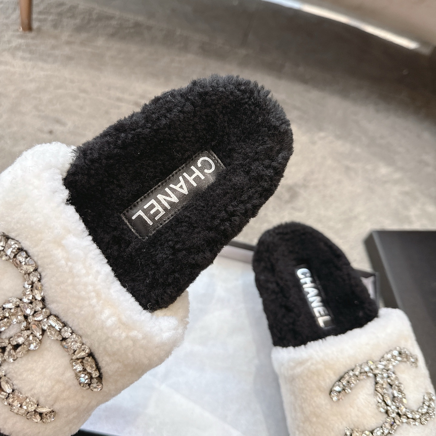 A pair of black and white Chanel shearling slides with crystal-encrusted CC logos presented in a black designer box. - Hình 8