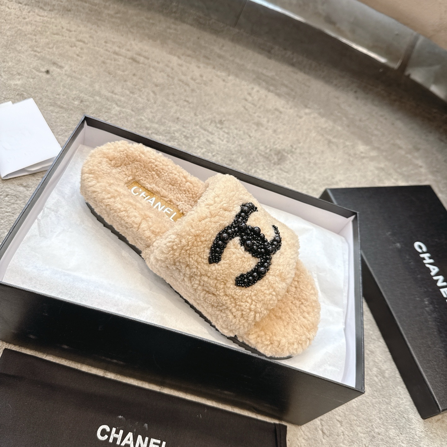 Pair of Chanel beige fuzzy shearling slide sandals with black beaded interlocking CC logo in original packaging. - Hình 4