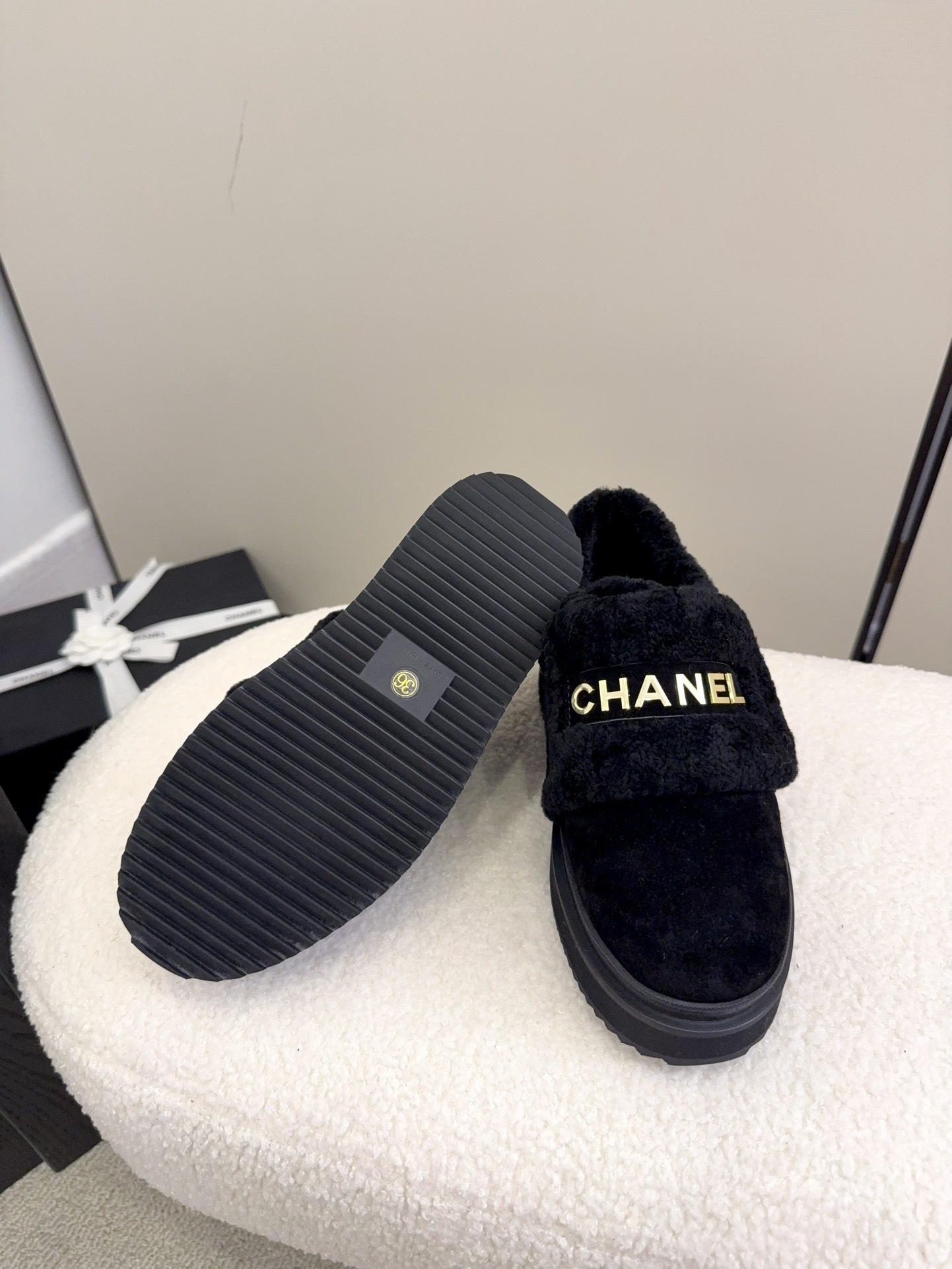 Pair of black Chanel shearling platform loafers with gold logo lettering on a white textured surface - Hình 9