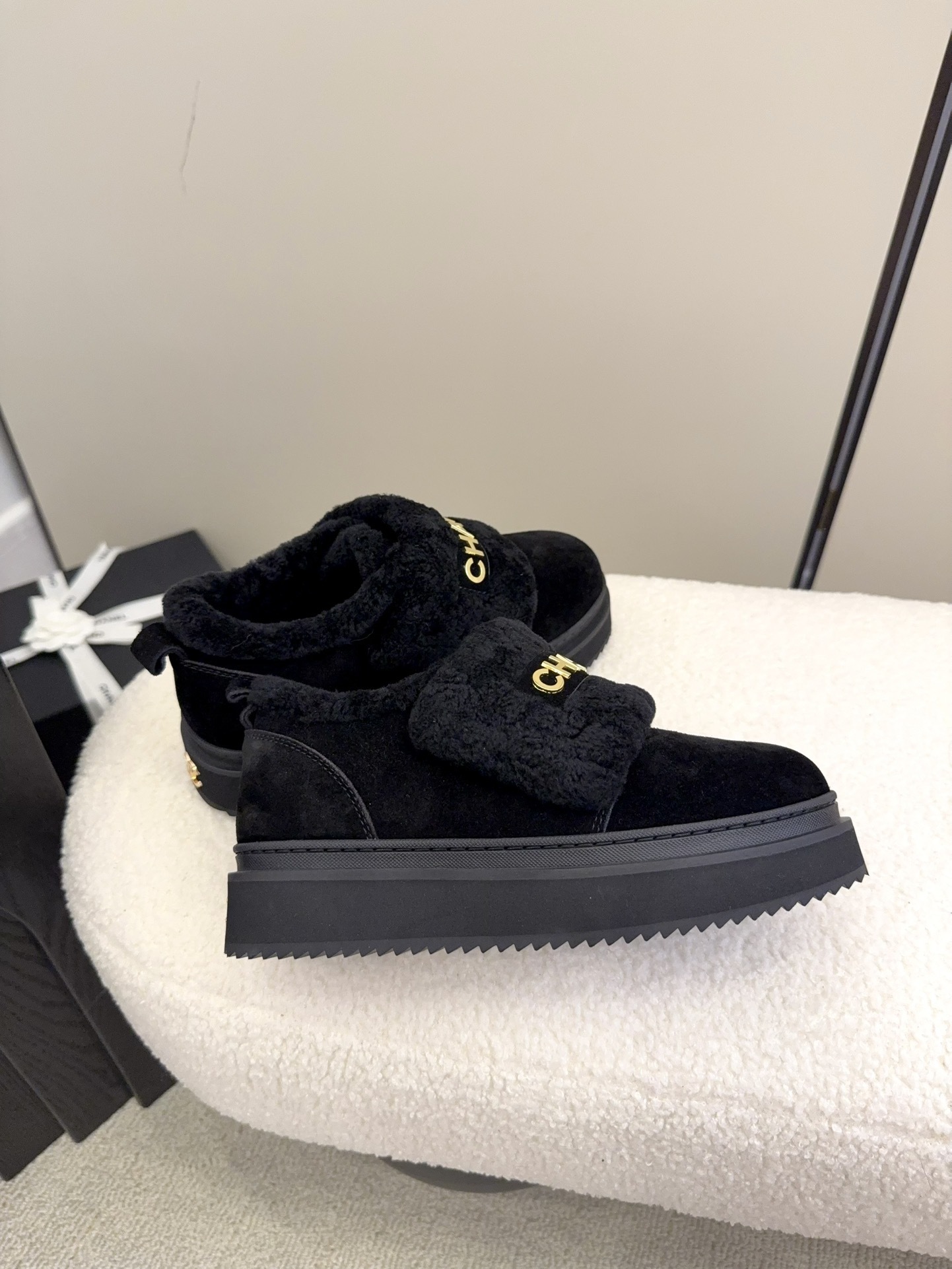 Pair of black Chanel shearling platform loafers with gold logo lettering on a white textured surface - Hình 8