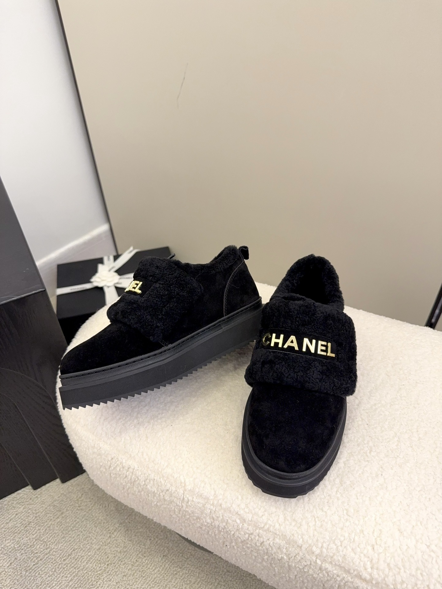 Pair of black Chanel shearling platform loafers with gold logo lettering on a white textured surface - Hình 5