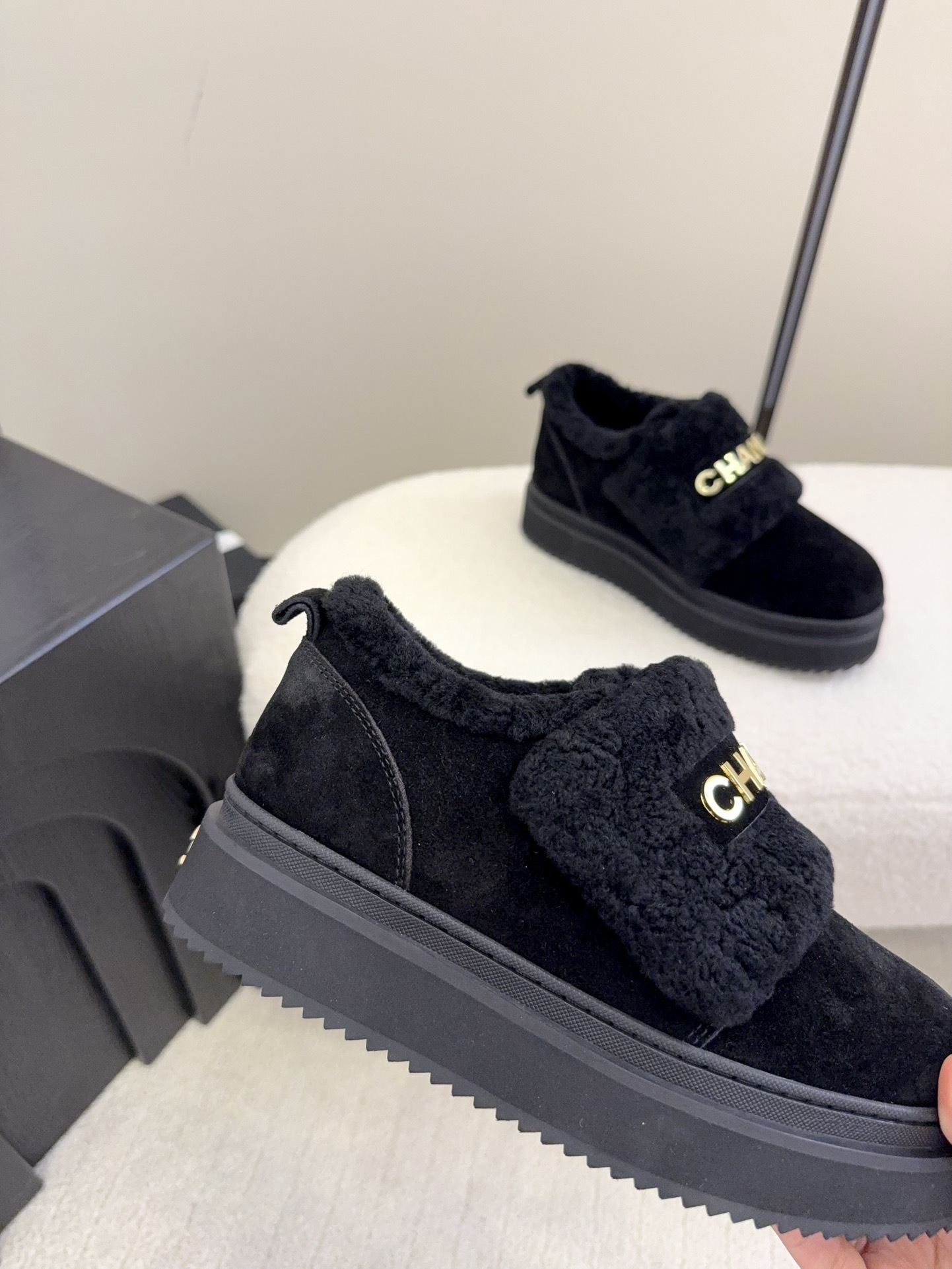 Pair of black Chanel shearling platform loafers with gold logo lettering on a white textured surface - Hình 4