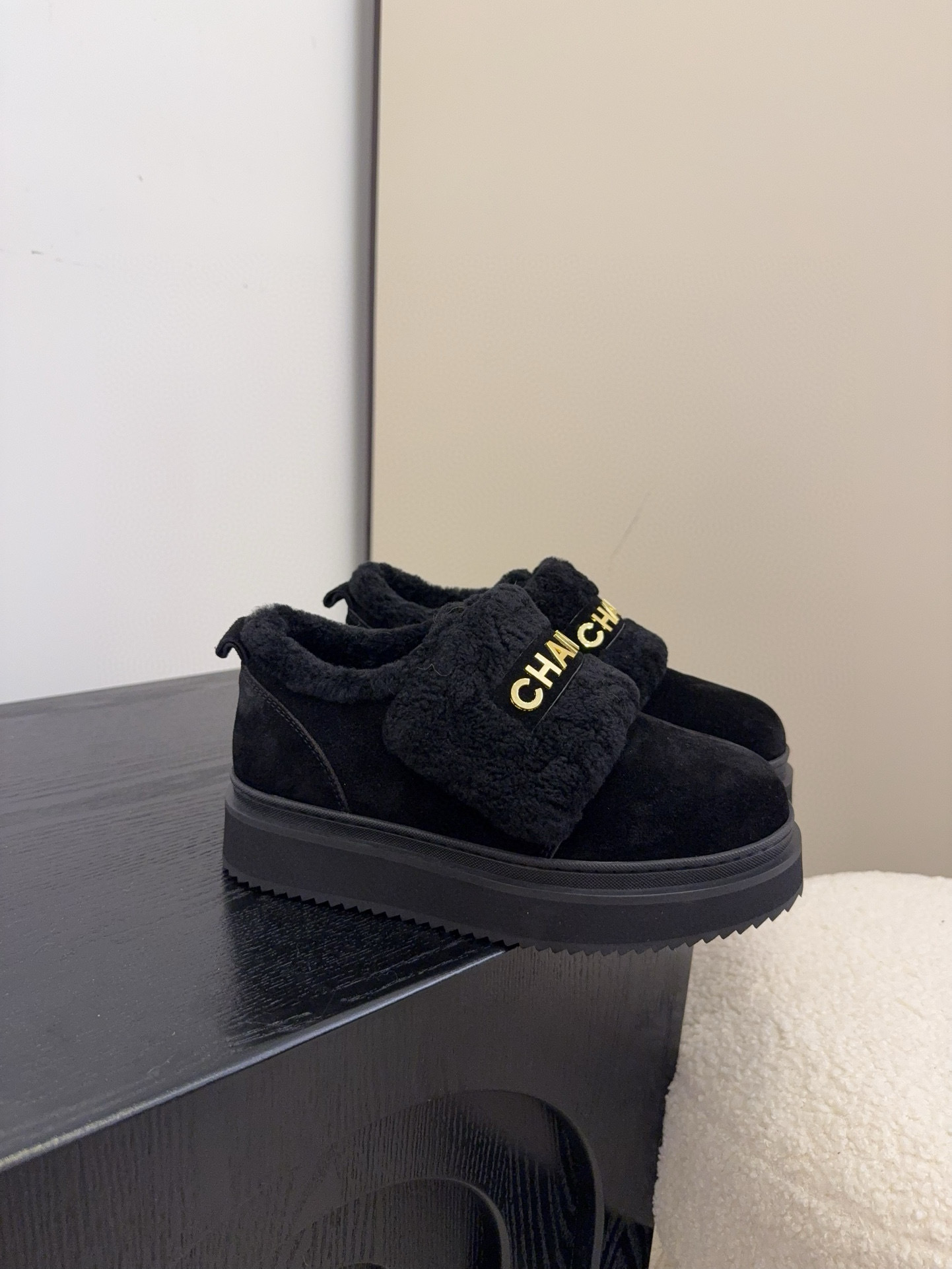 Pair of black Chanel shearling platform loafers with gold logo lettering on a white textured surface - Hình 3