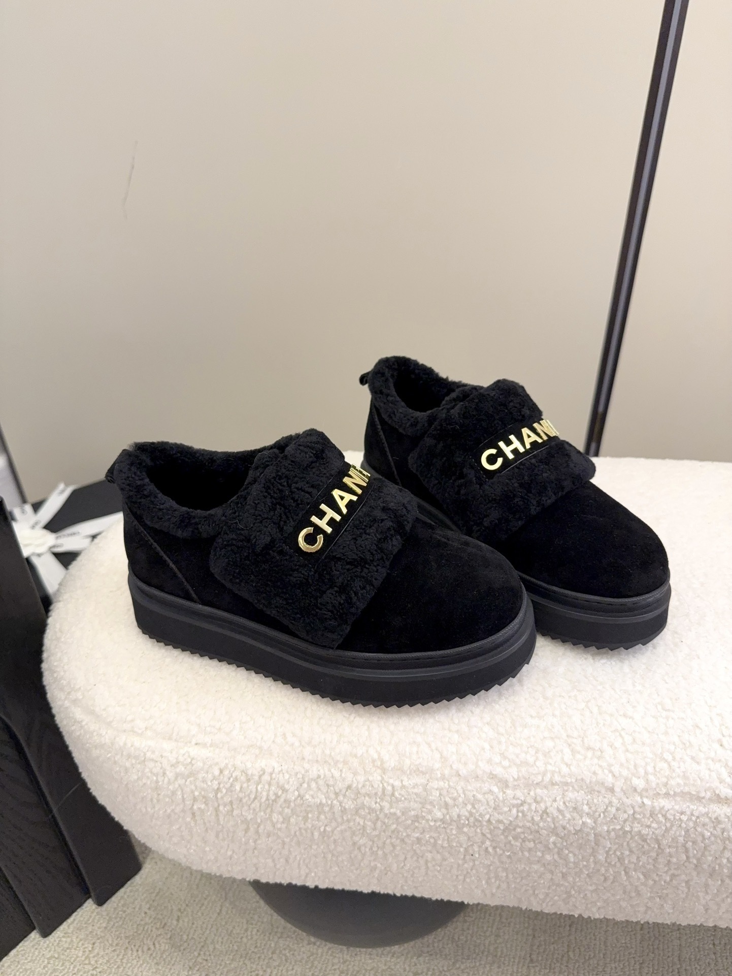 Pair of black Chanel shearling platform loafers with gold logo lettering on a white textured surface - Hình 2