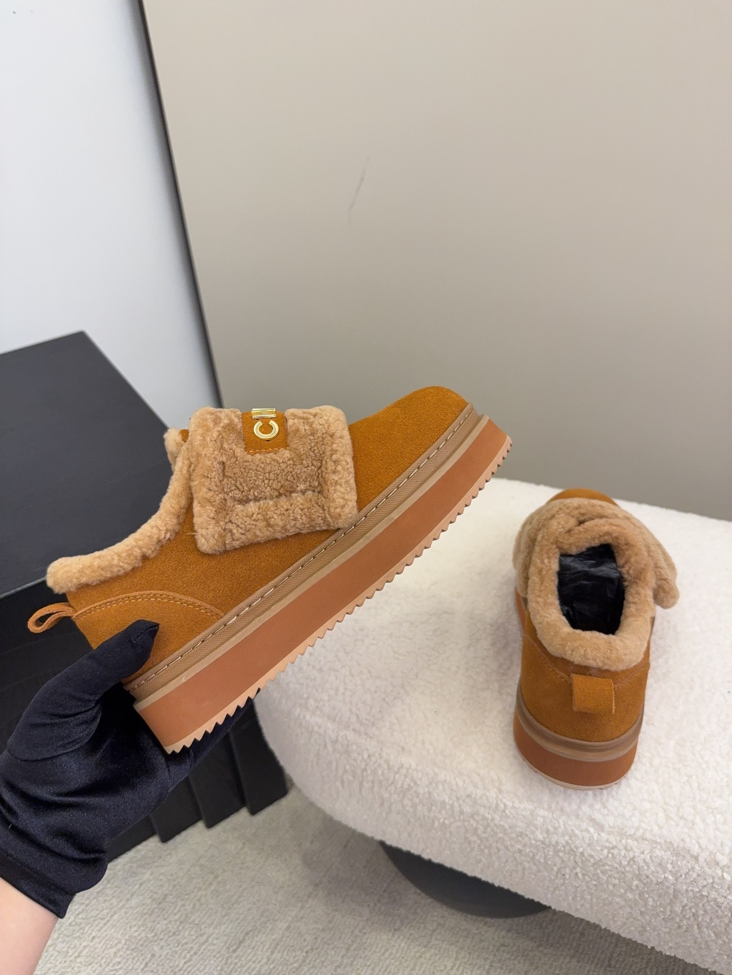 Pair of tan Chanel suede platform sneakers with shearling lining and gold logo strap on a white textured surface. - Hình 9