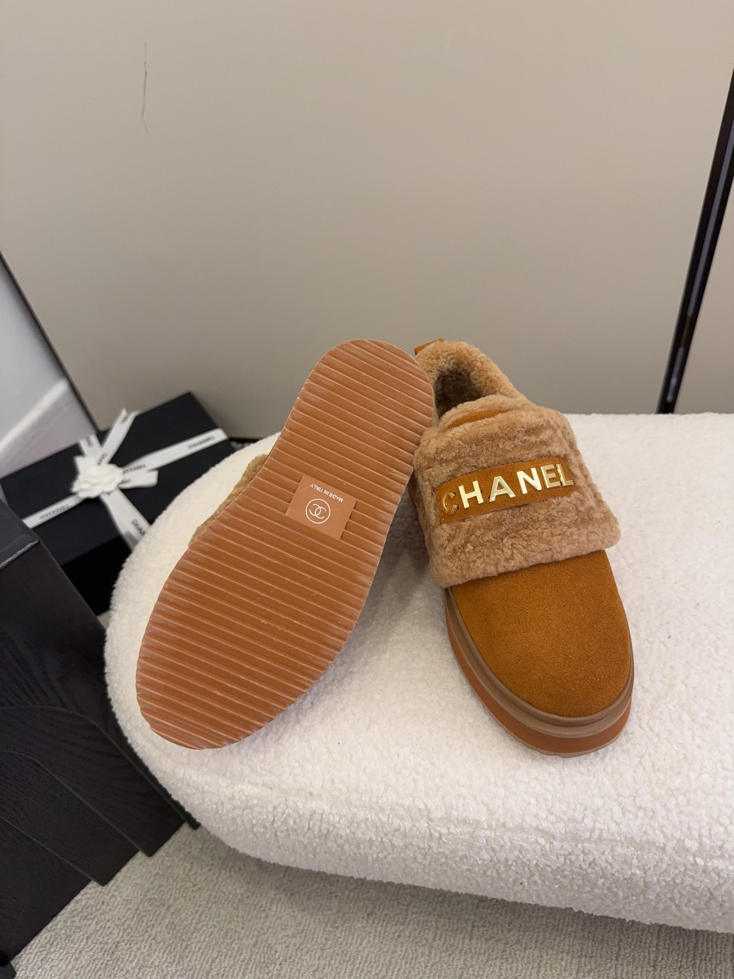 Pair of tan Chanel suede platform sneakers with shearling lining and gold logo strap on a white textured surface. - Hình 7