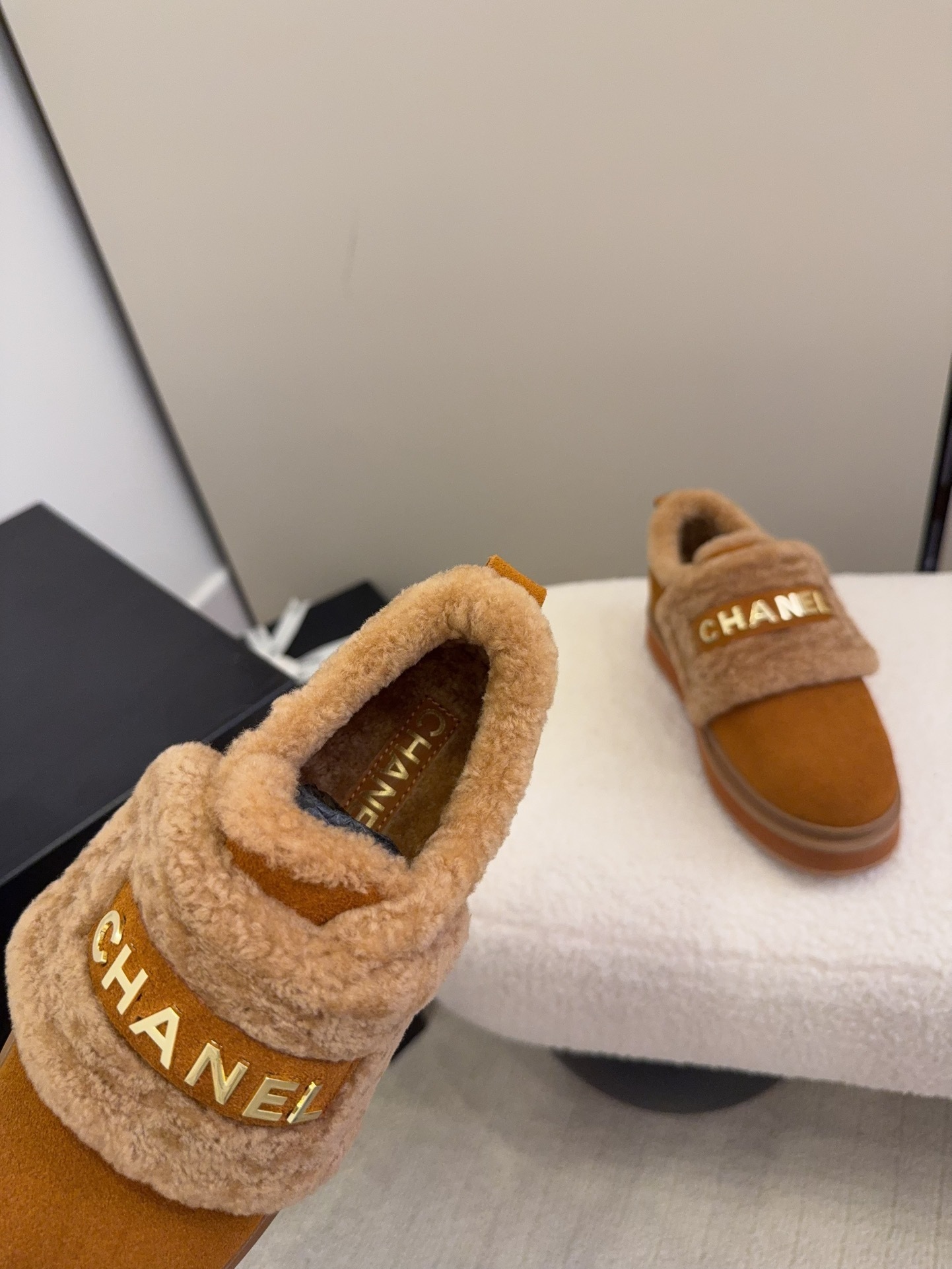 Pair of tan Chanel suede platform sneakers with shearling lining and gold logo strap on a white textured surface. - Hình 6