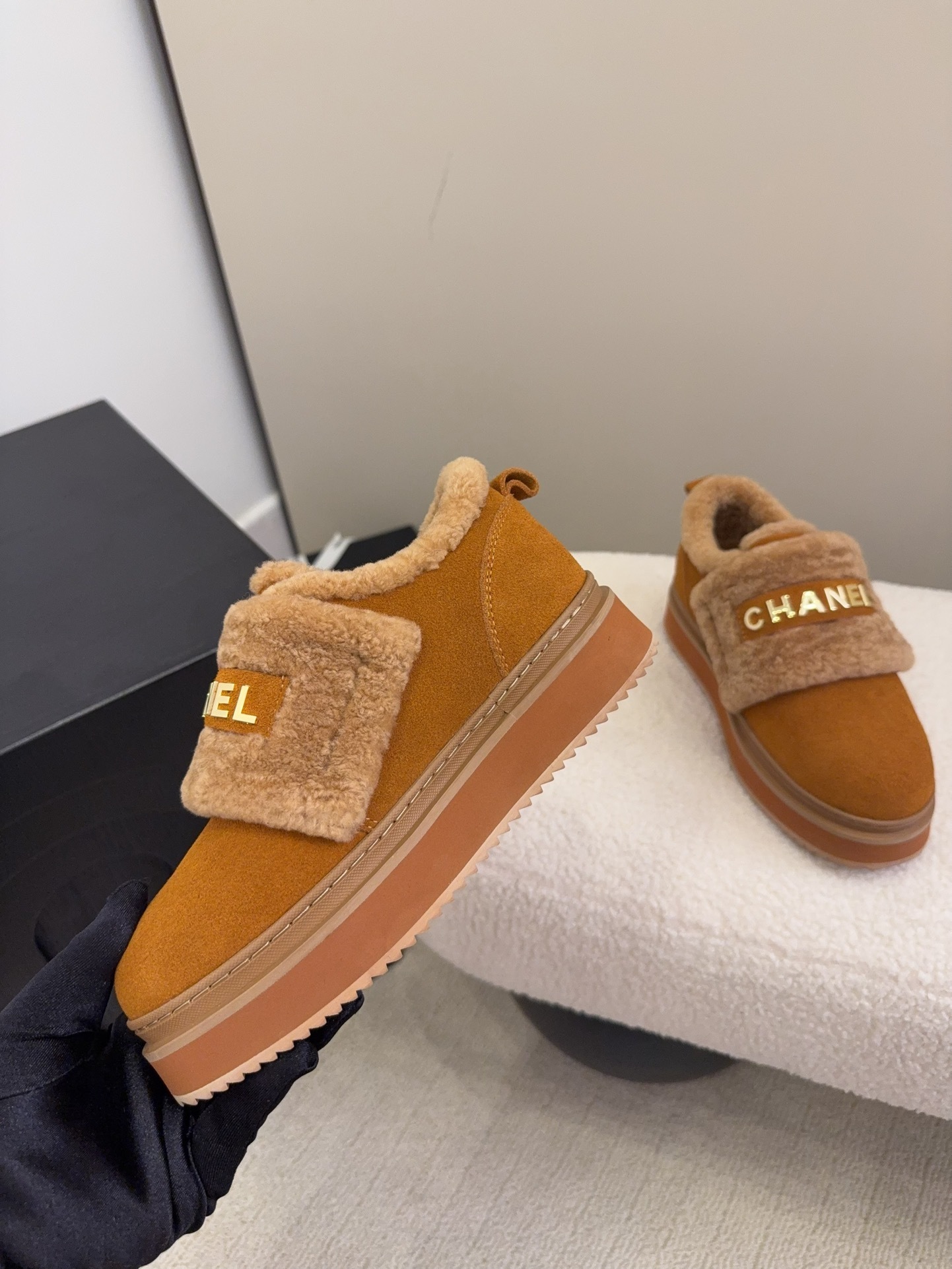 Pair of tan Chanel suede platform sneakers with shearling lining and gold logo strap on a white textured surface. - Hình 5