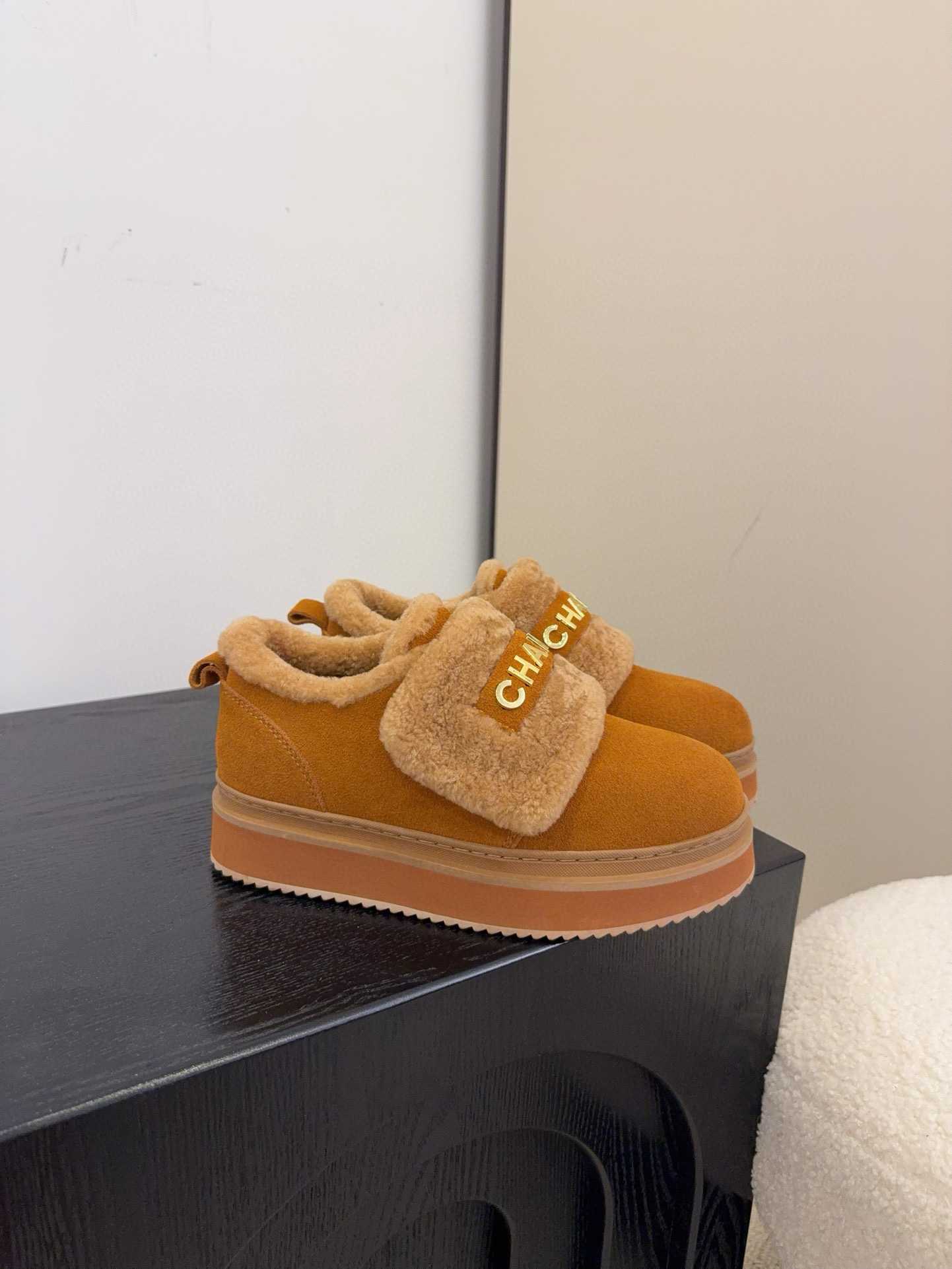 Pair of tan Chanel suede platform sneakers with shearling lining and gold logo strap on a white textured surface. - Hình 3