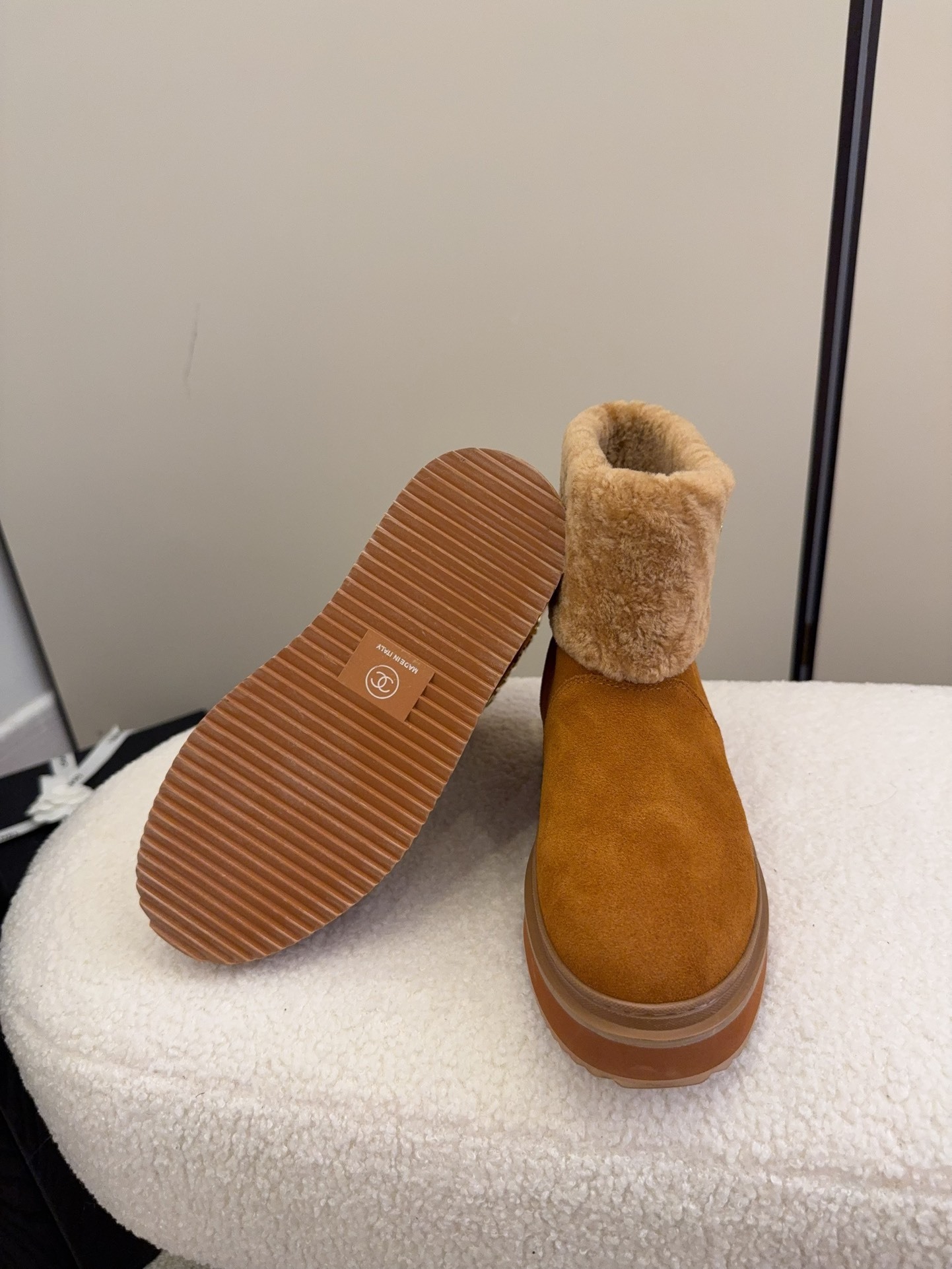 A pair of camel-colored Chanel suede platform boots with tan shearling trim and gold logo detail on a white textured surface. - Hình 6