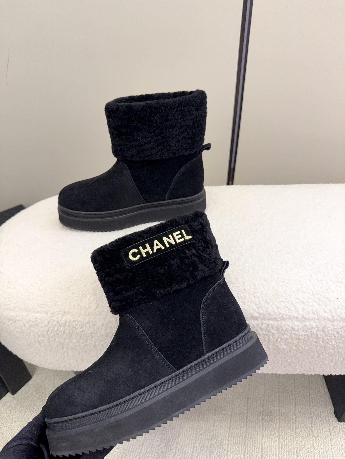 Pair of black Chanel suede ankle boots with faux fur trim and gold logo on a white surface - Hình 7