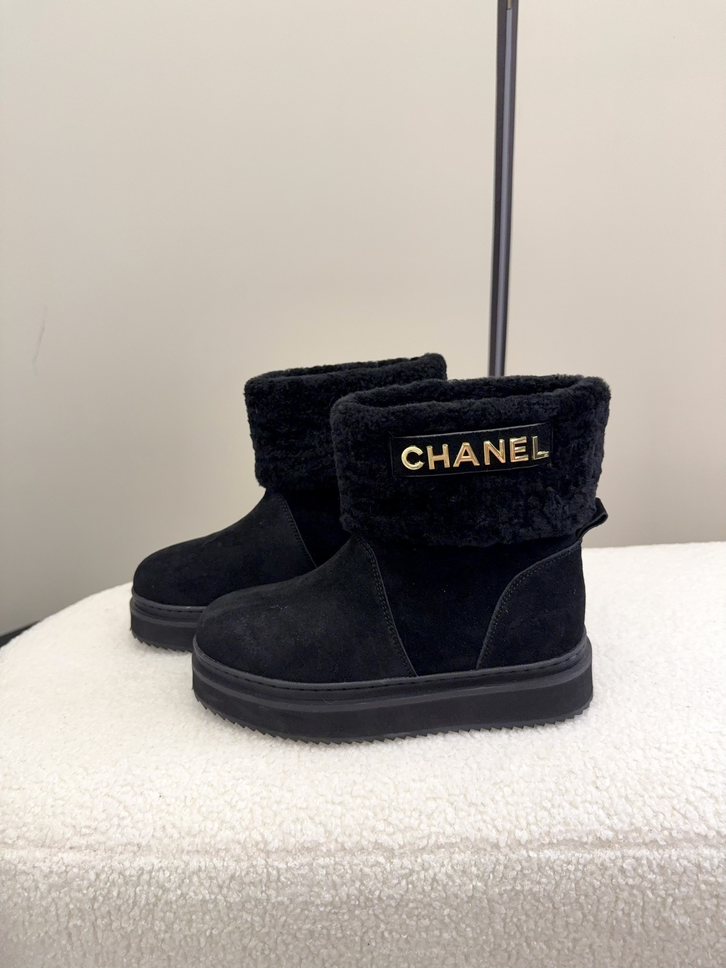 Pair of black Chanel suede ankle boots with faux fur trim and gold logo on a white surface - Hình 6