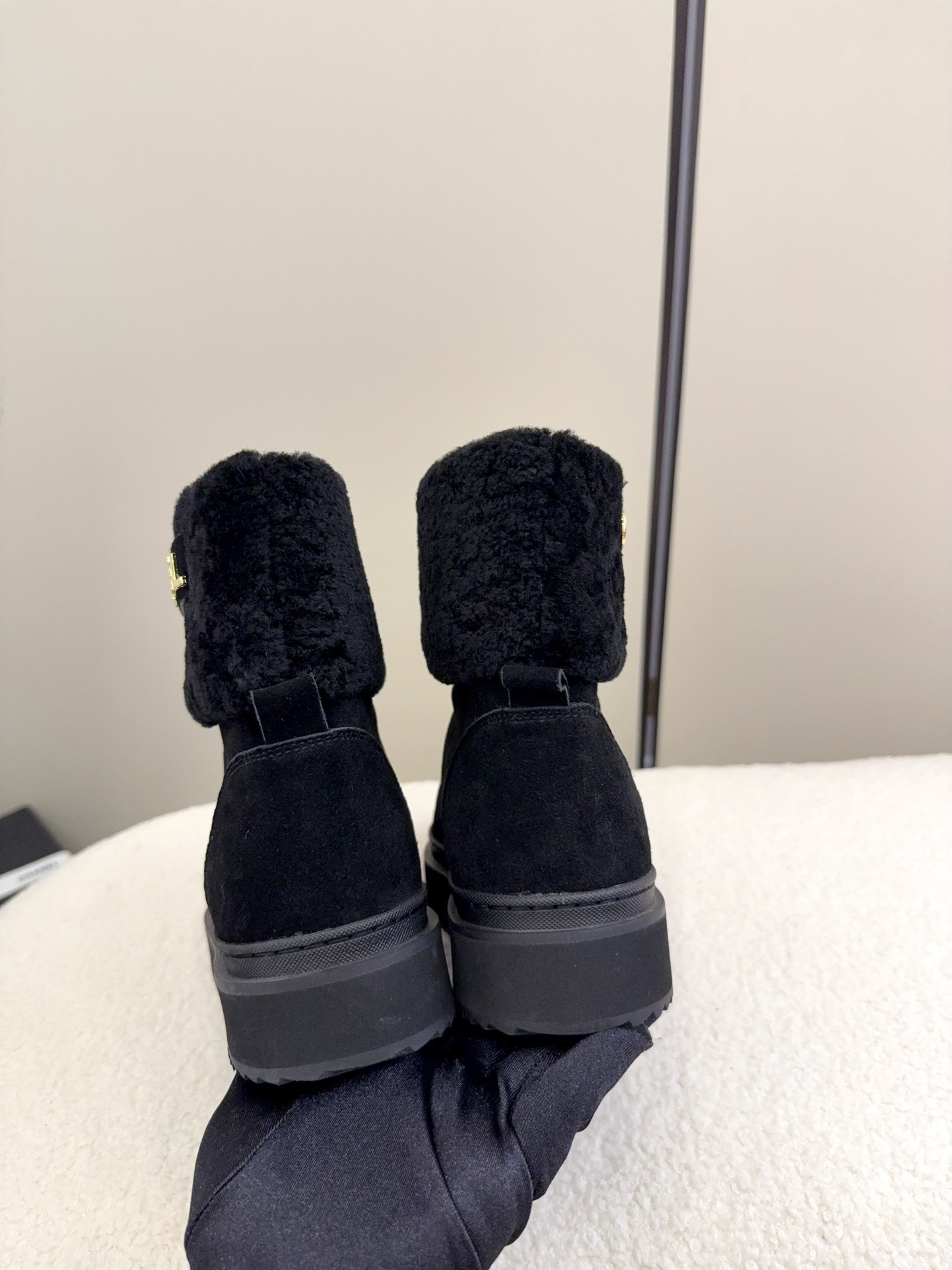 Pair of black Chanel suede ankle boots with faux fur trim and gold logo on a white surface - Hình 5