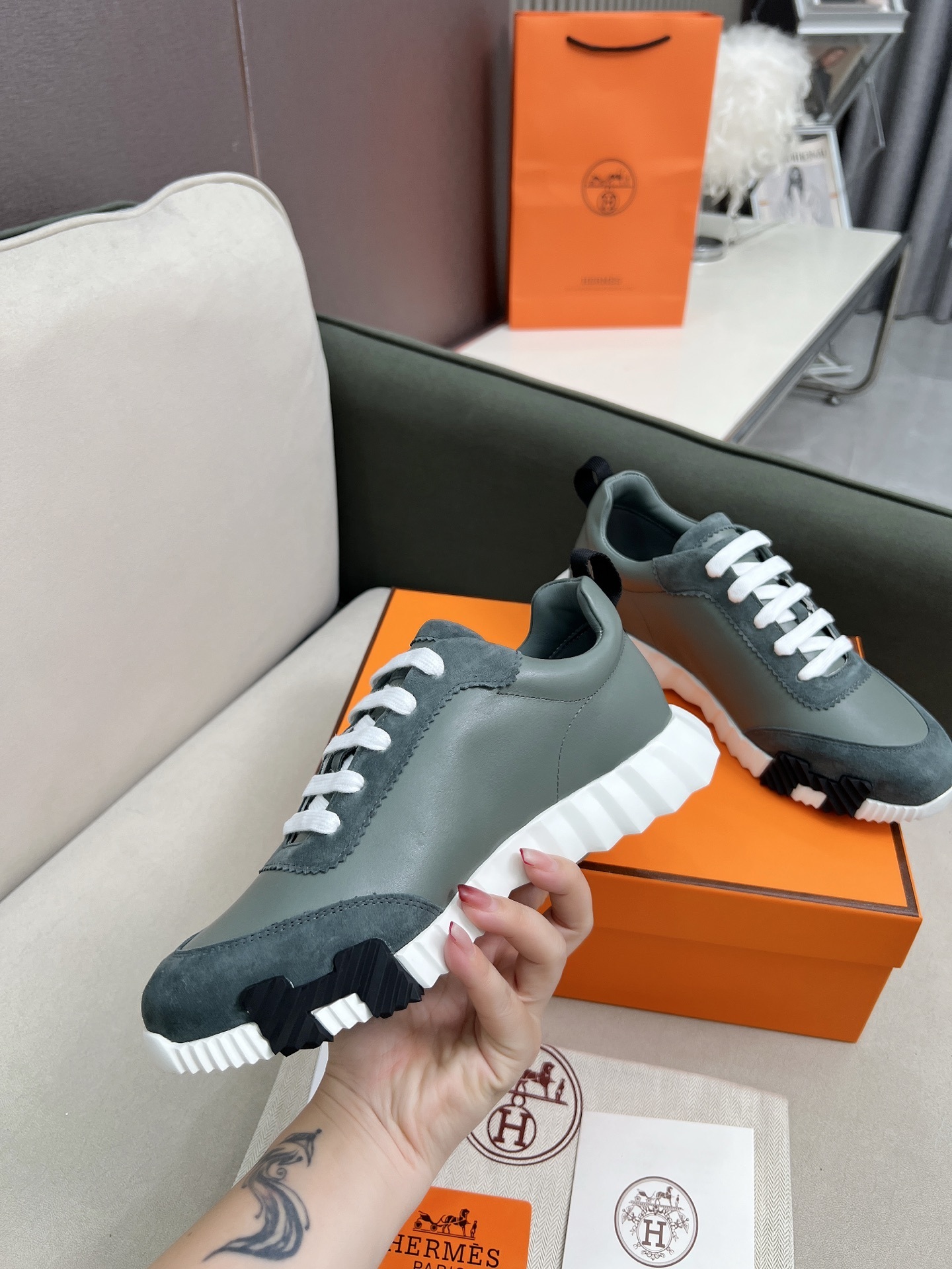 Pair of Chanel metallic silver and white mesh sneakers on a black box with a luxury shopping bag. - Hình 9