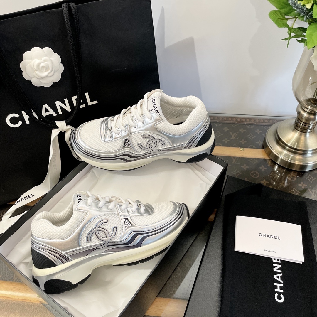 Pair of Chanel metallic silver and white mesh sneakers on a black box with a luxury shopping bag. - Hình 6