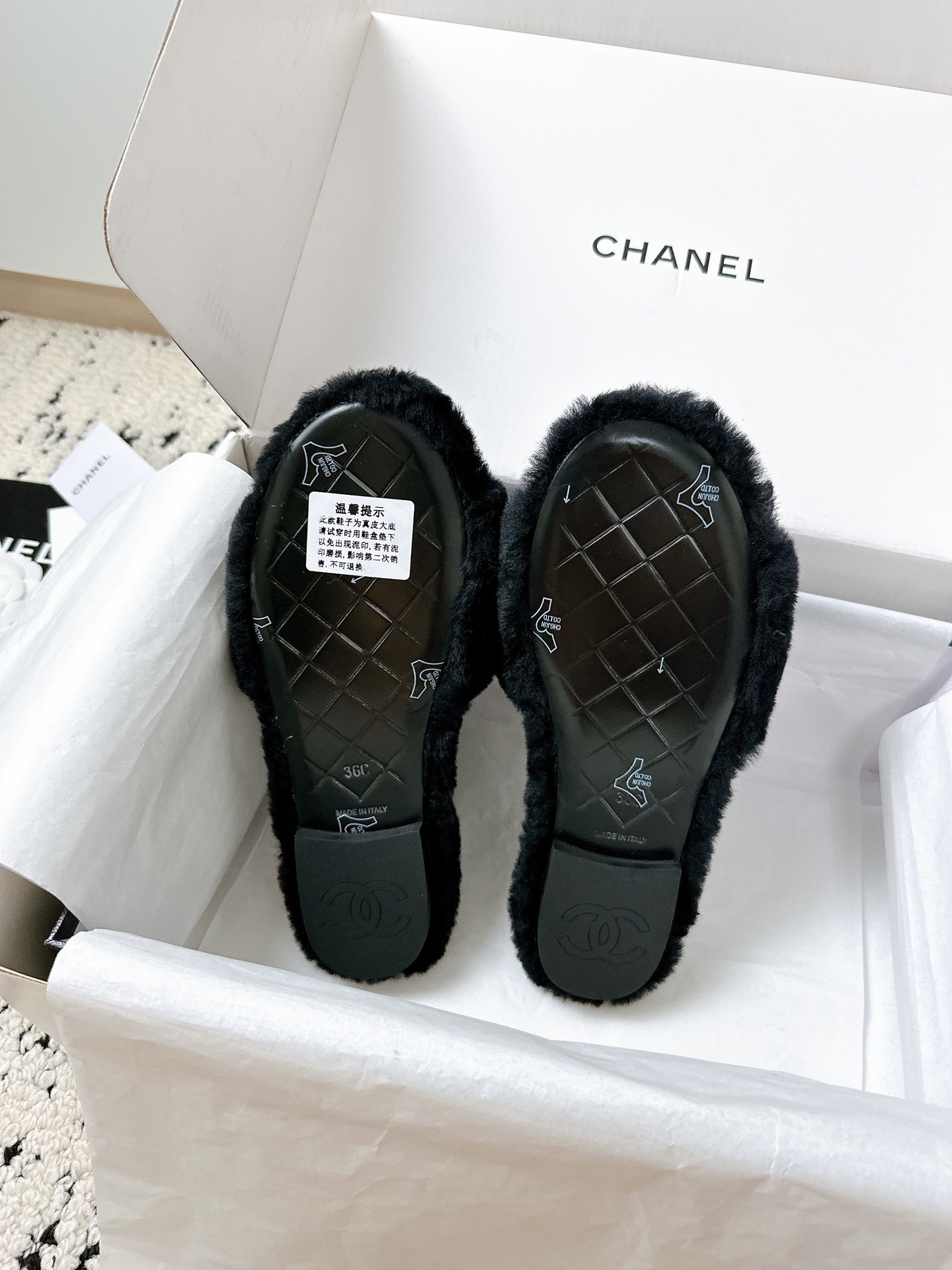 A pair of black plush shearling Chanel slippers featuring gold interlocking CC logos, presented in their original white designer box. - Hình 8