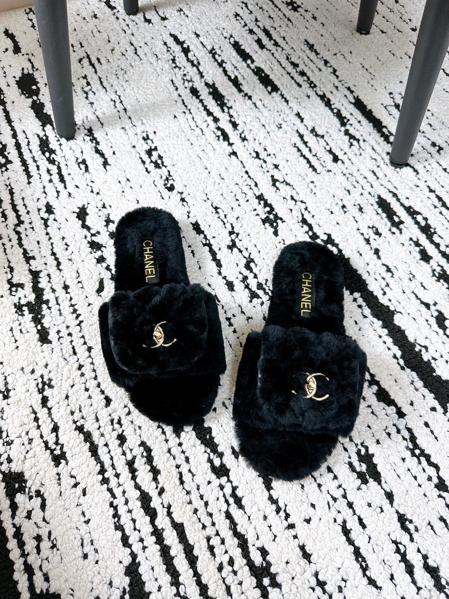 A pair of black plush shearling Chanel slippers featuring gold interlocking CC logos, presented in their original white designer box. - Hình 3