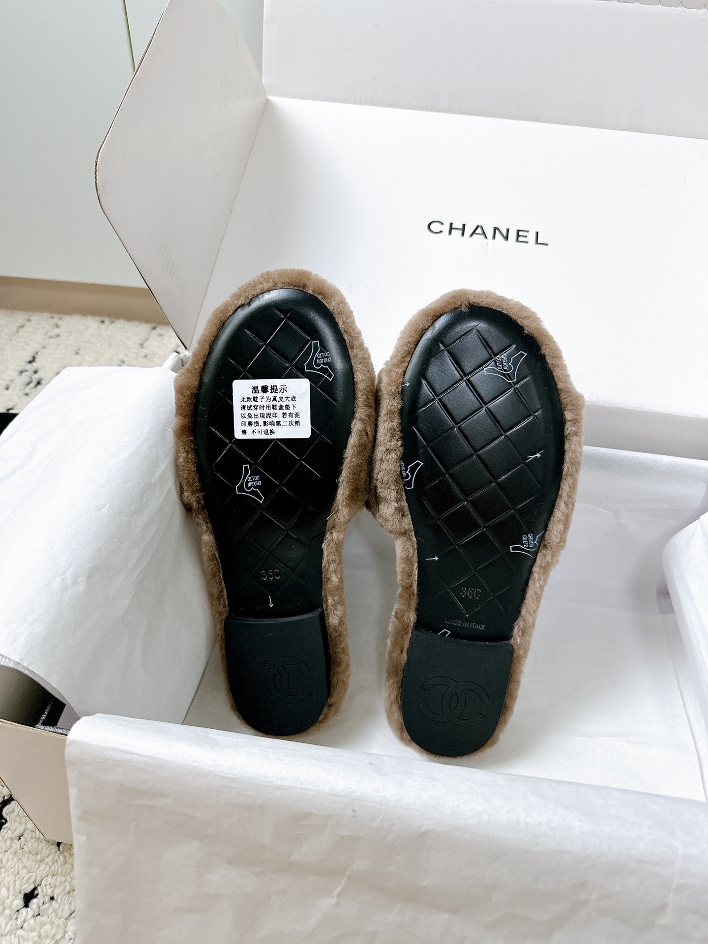 A pair of luxurious brown Chanel quilted shearling fur slippers with gold CC logo displayed in a white designer box. - Hình 9
