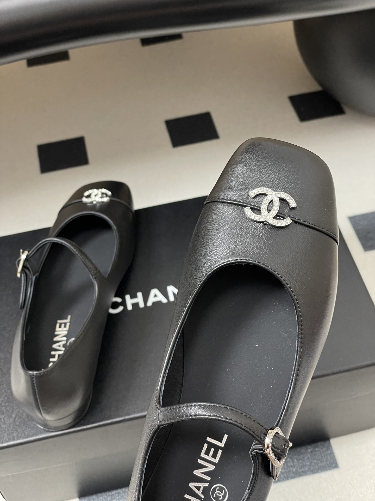 A pair of black leather Chanel Mary Jane flats featuring crystal-embellished CC logos on the toes and crystal buckles on the straps. - Hình 9