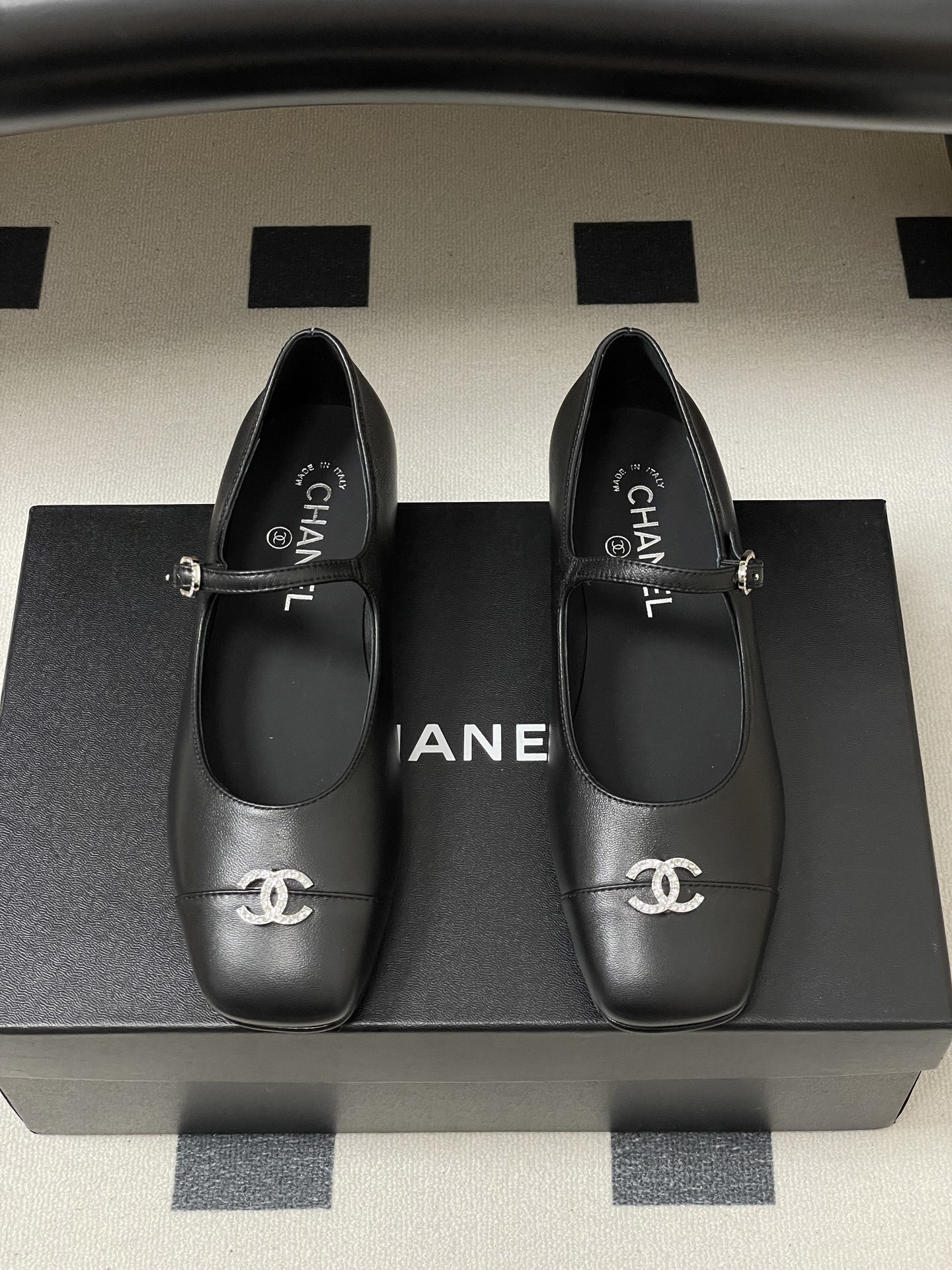 A pair of black leather Chanel Mary Jane flats featuring crystal-embellished CC logos on the toes and crystal buckles on the straps. - Hình 5